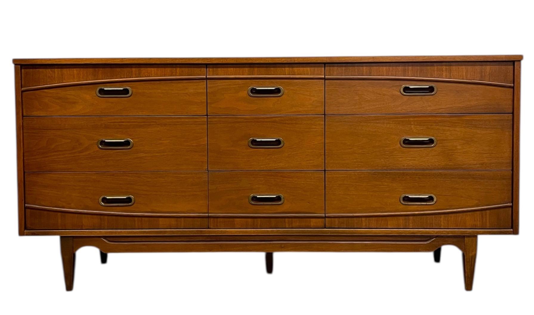  This mid-century modern 9-drawer dresser was made by Hooker, as indicated by the branded maker's mark inside the top drawer. Designed with clean lines and a warm wood finish, the piece reflects the refined craftsmanship and understated elegance