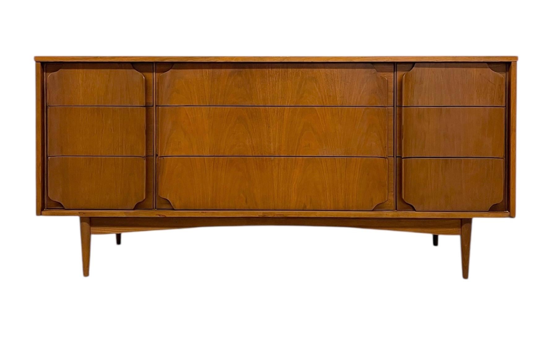 A beautifully crafted mid-century modern dresser featuring nine smoothly operating drawers and distinctive sculpted drawer fronts. This piece showcases clean lines, warm tones, and the iconic organic curves associated with mid-century American