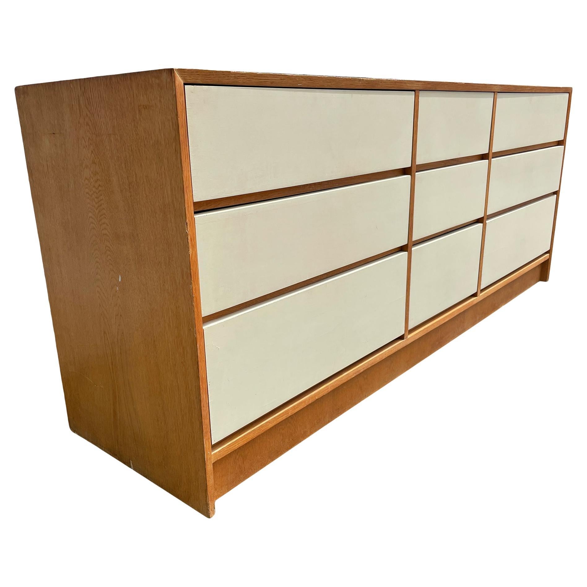 Mid-Century Modern 9 drawer oak credenza or dresser circa 1960s well built. Has 9 off whit lacquered geometrical long drawers and 3 center narrow drawers with lower hidden pulls. Made in Poland Labeled on back. Located in Brooklyn NYC.