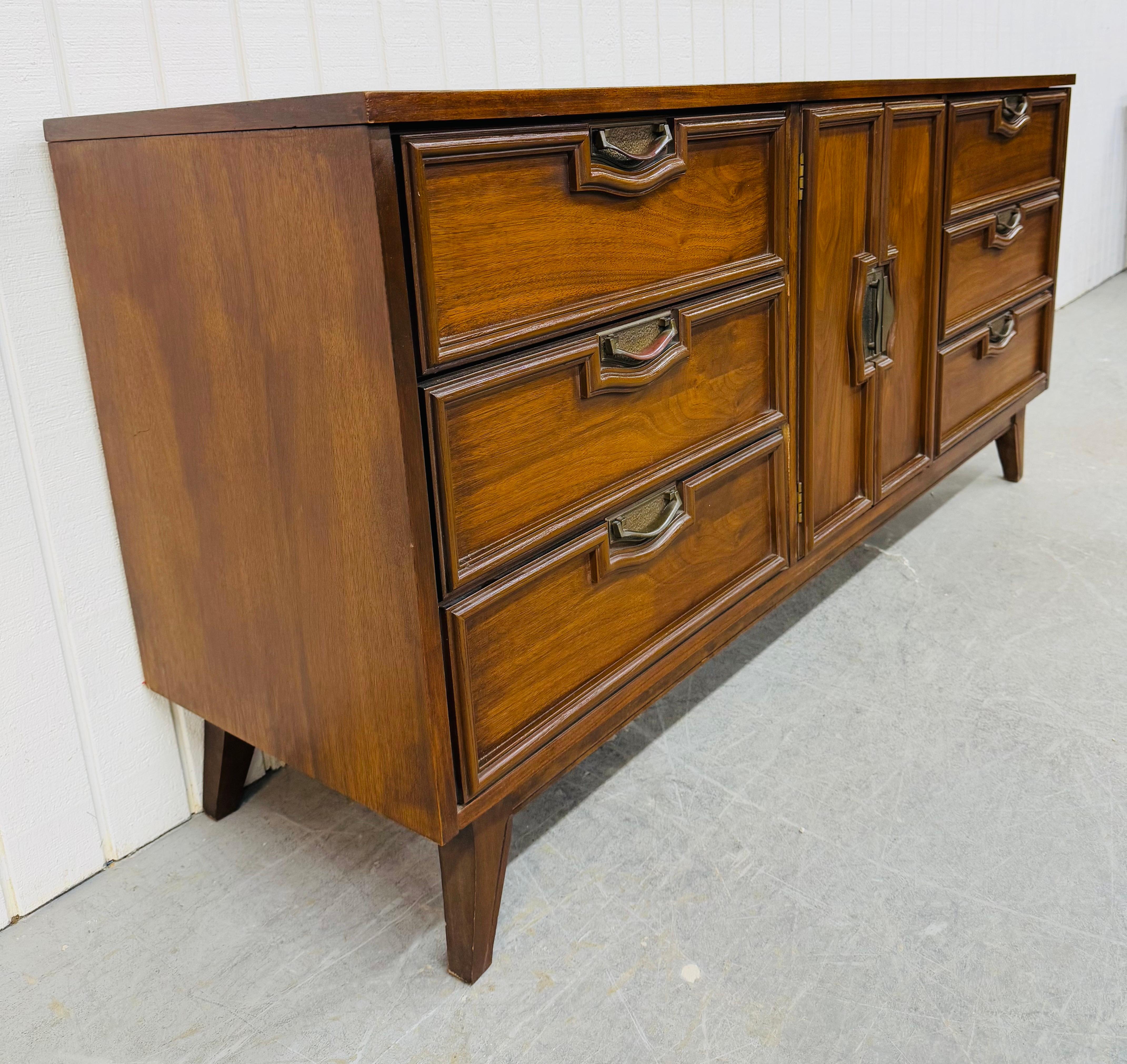 Questo annuncio si riferisce a un comò in noce a 9 cassetti in stile Mid-Century Modern. Il design è lineare, i cassetti sono tre per ogni lato, l'anta centrale si apre su cassetti nascosti, la ferramenta è originale, le gambe sono moderne e la
