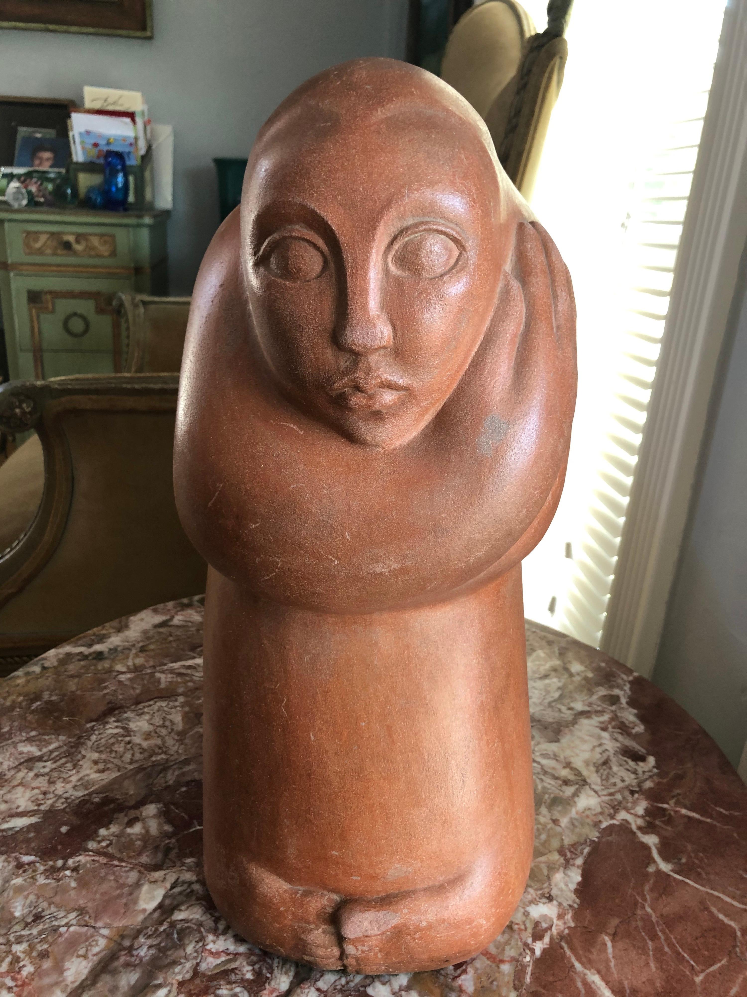 Mid-Century Modern abstract statue of a woman. Finely sculpted figure of a woman with her arms wrapped around herself in a sitting position. The sculpture has a smooth, matte coral colored washed finish.
In the style of Modigliani or Inuit Folk Art.