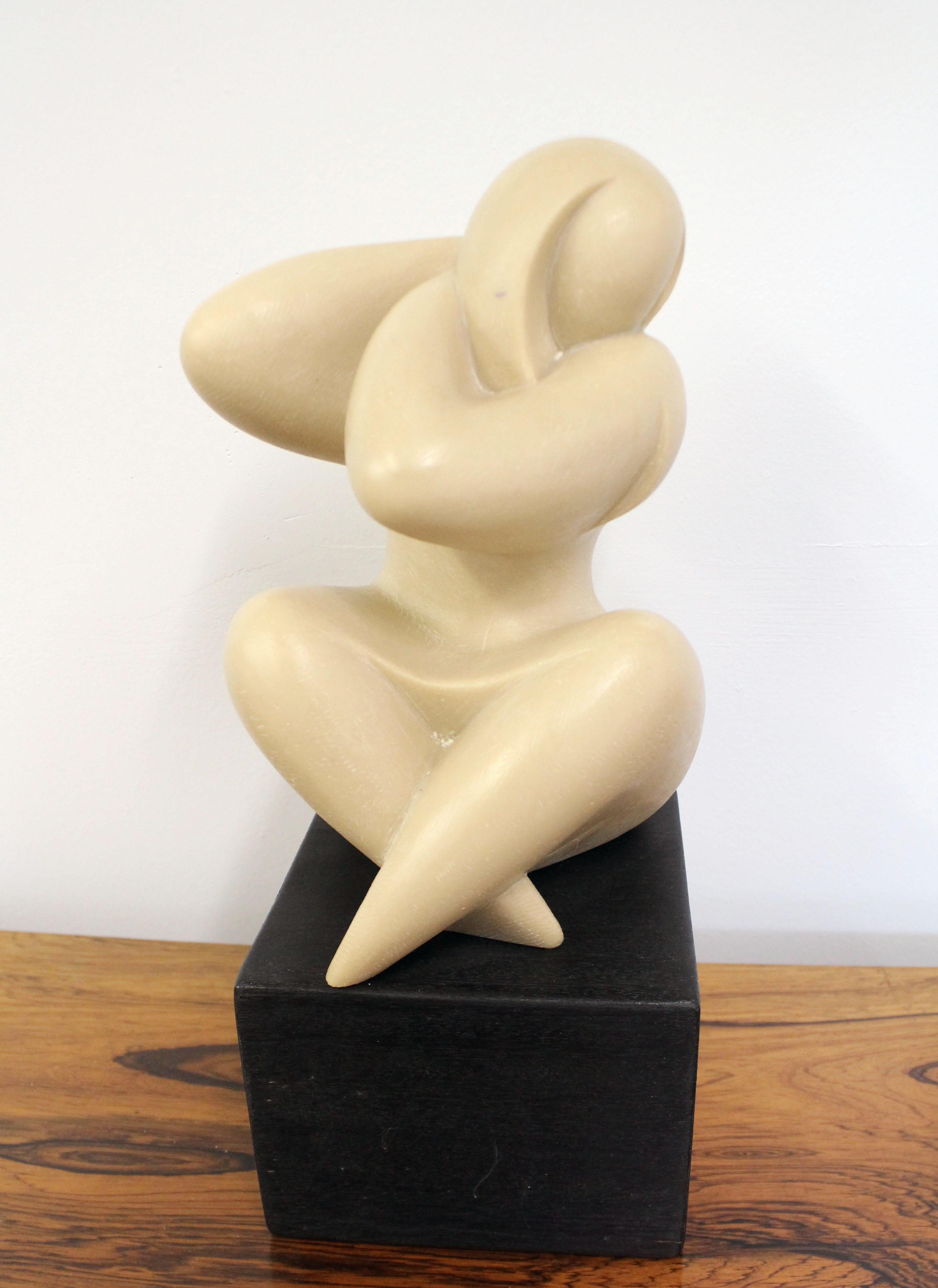 Offered is a vintage Mid-Century Modern sculpture by J. Martinek. This piece features a resin composite sculpture of a seated curvy woman on a wood block. It is in good condition for its age but shows some flaws - imperfection/crack in back