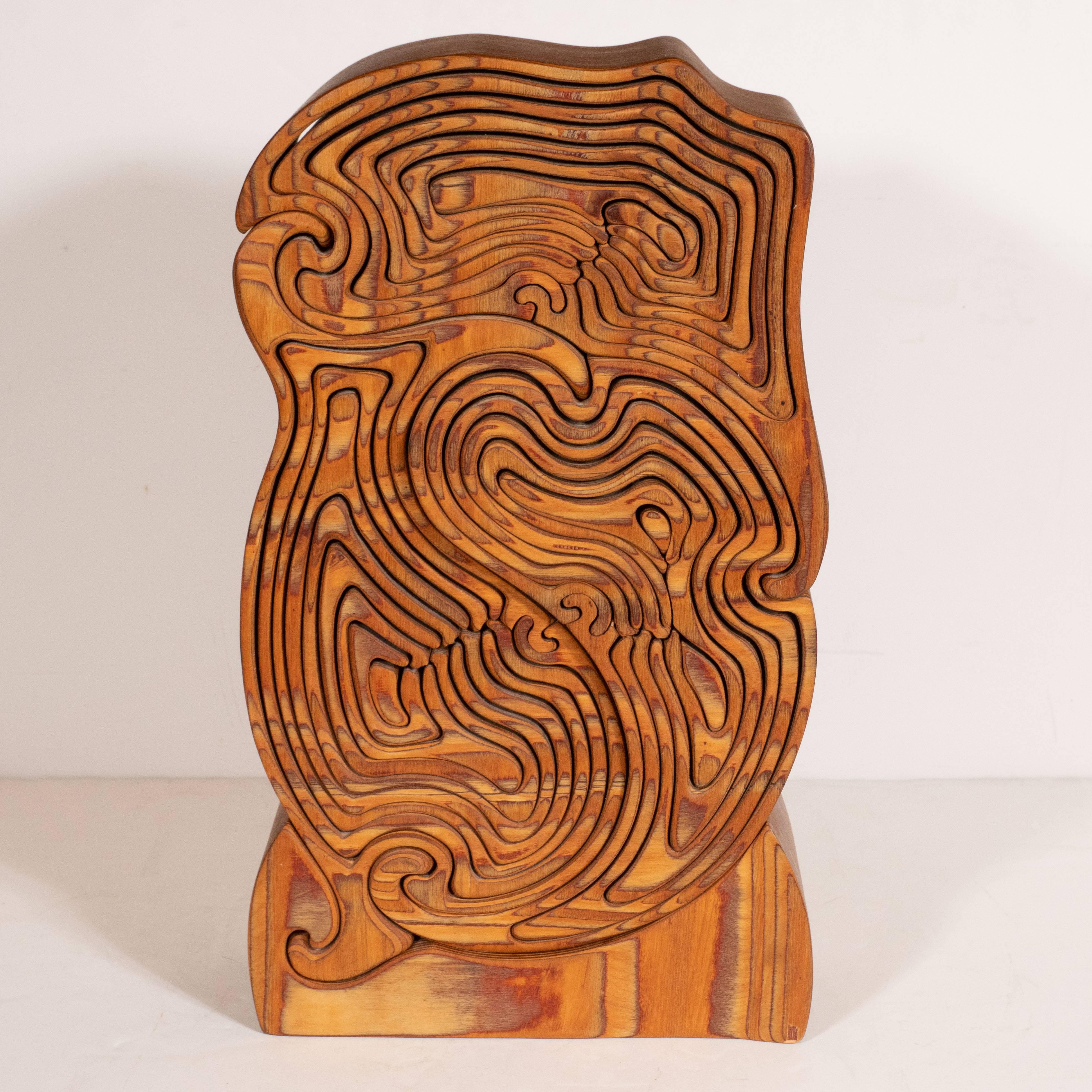 This kinetic and impeccably crafted olive wood sculpture was realized, by hand, in the United States, circa 1970. It offers a an abundance of intertwining curvilinear forms that fit together, like abstracted nesting dolls. The dimensional form