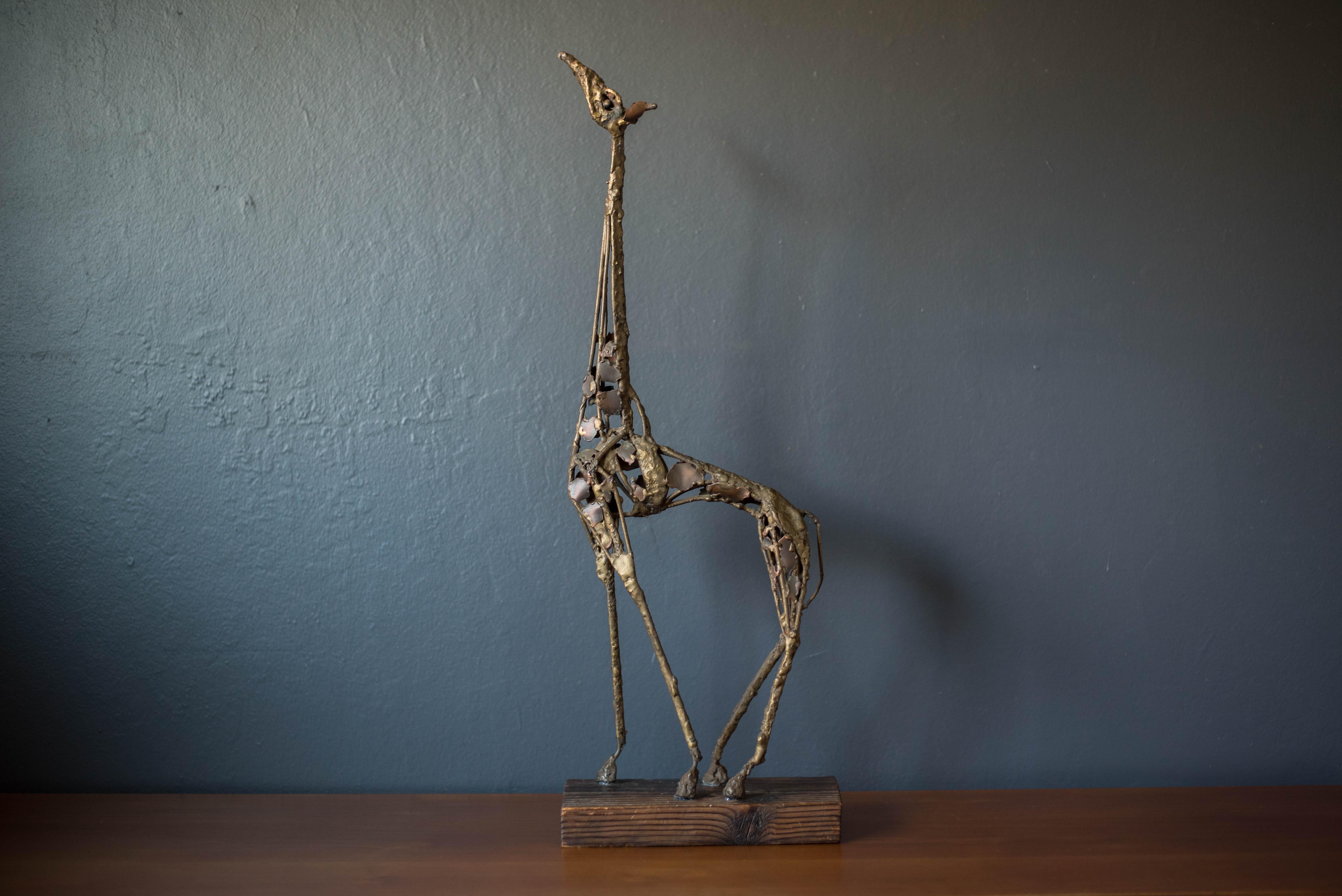 Vintage abstract Brutalist freestanding giraffe sculpture on solid wood plank c. 1960's. This decorative accent piece adds depth and character to any space composed of mixed metals that display plenty of vintage patina.




