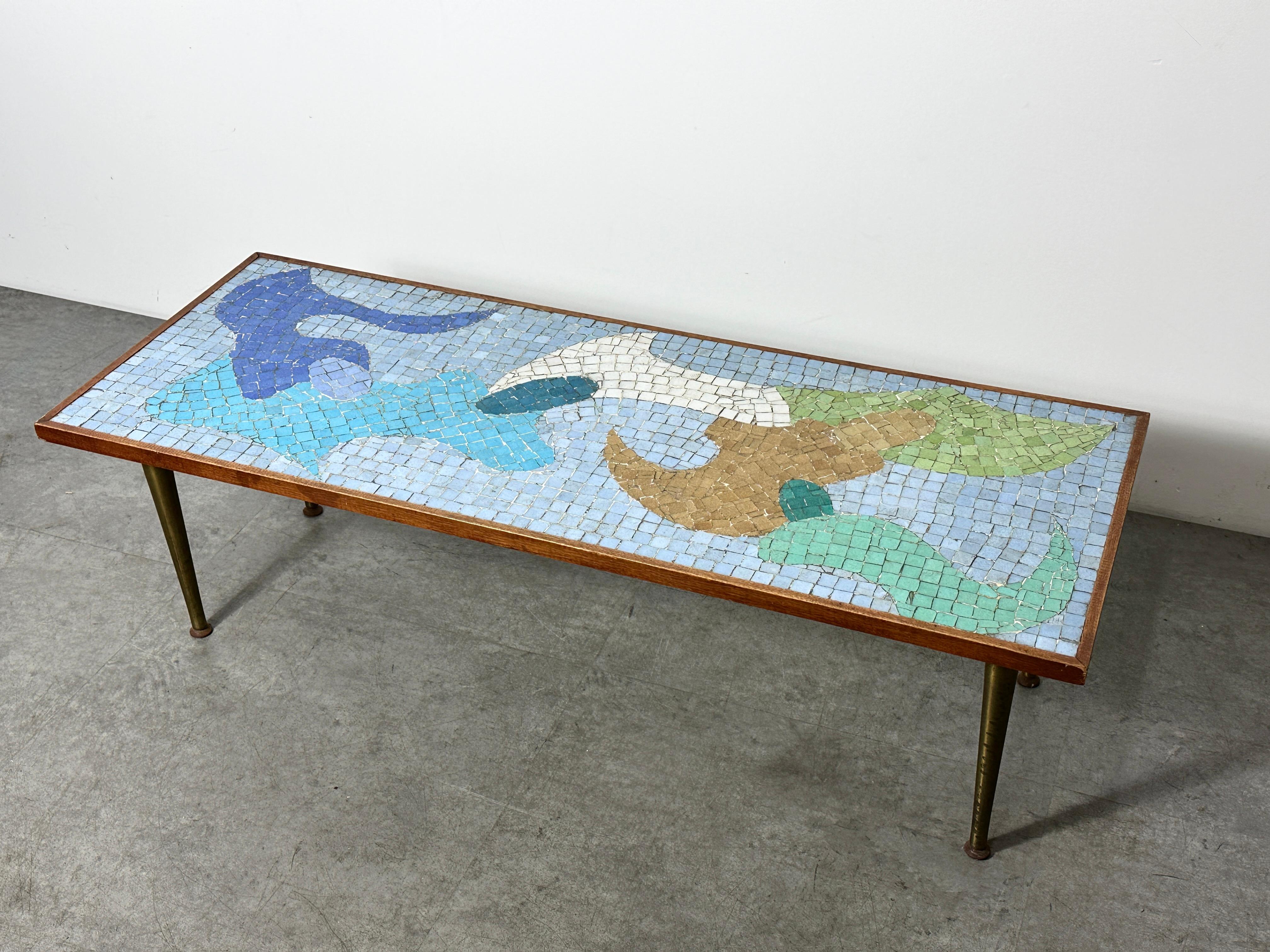 Incredible mosaic tile top coffee table created in the style of Evelyn Ackerman circa 1950s

Abstract modernist design formed of inlaid glass tiles in blues and greens 
Framed in walnut and supported by tapered brass legs

A distinct piece