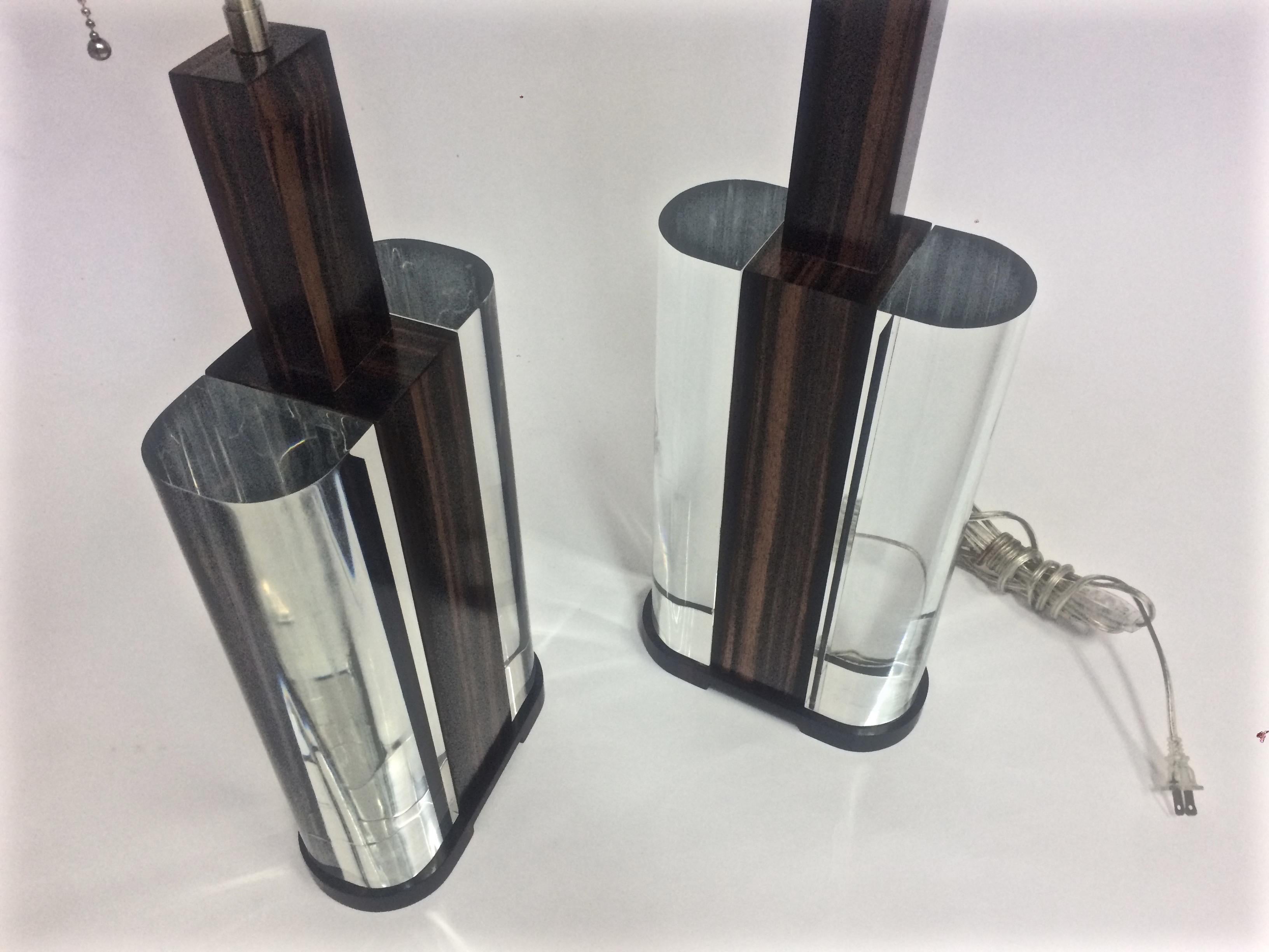 Mid-Century Modern acrylic and Macassar ebony wood matched pair of lamps, the solid satin stainless steel dual light sockets with a square finial to lock the shade and an on/off pull chain over a supporting Macassar ebony wood standard, the body is