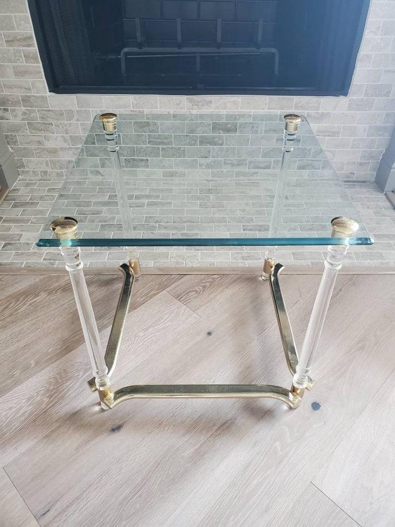 An elegant and stylish vintage side table, circa 1970s, Italian modern design, finished in luxurious Hollywood Regency / Glam taste, having a thick square glass top with nicely patinated brass tone accents and smooth beveled edge, over tubular