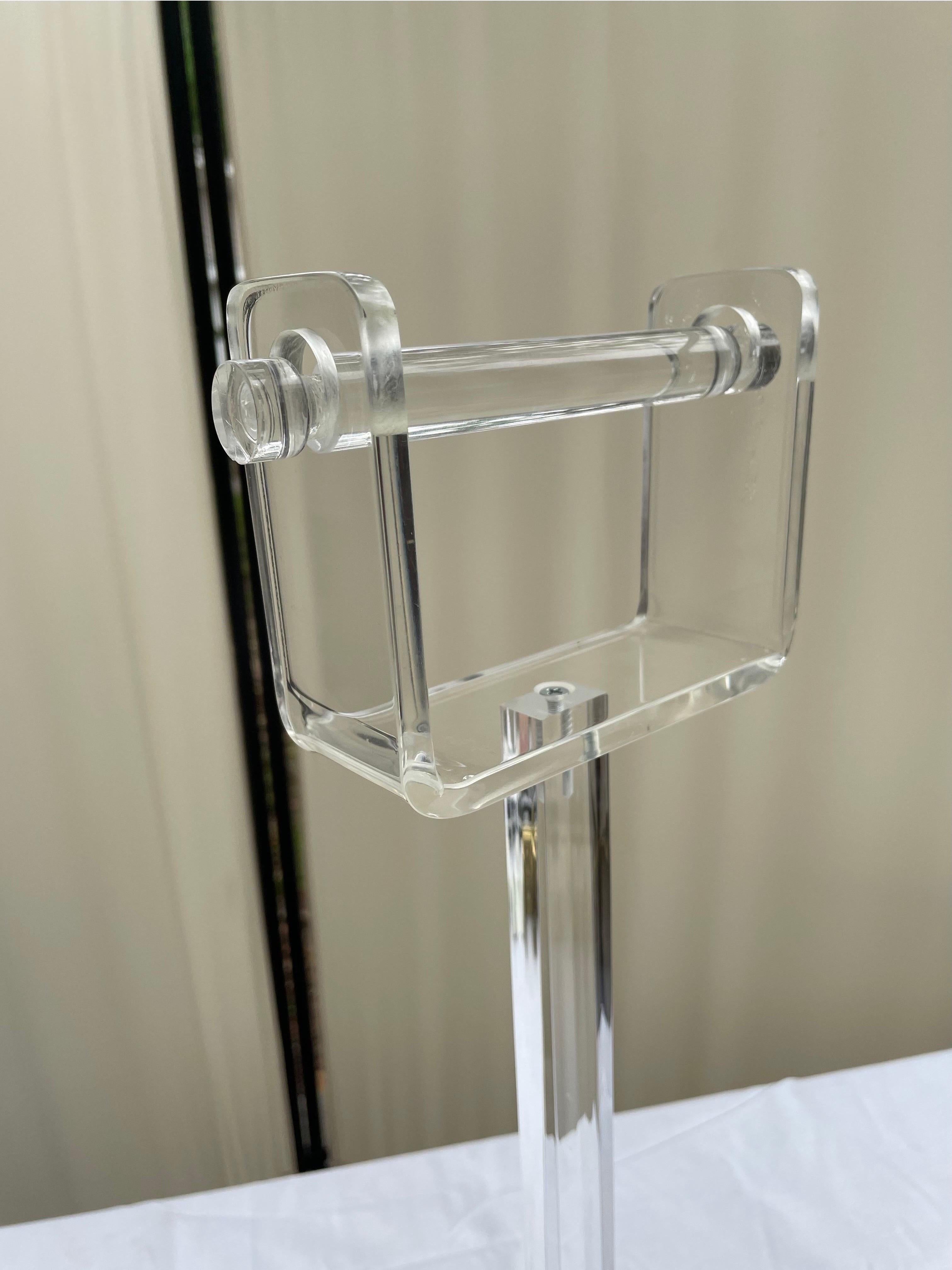 Mid-Century Modern clear lucite free standing toilet paper holder. This item is super chic and totally translucent. Made in the USA during the 1970s, it is in fantastic condition. Replacing the roll of toilet paper is very easy to do. Simple lift