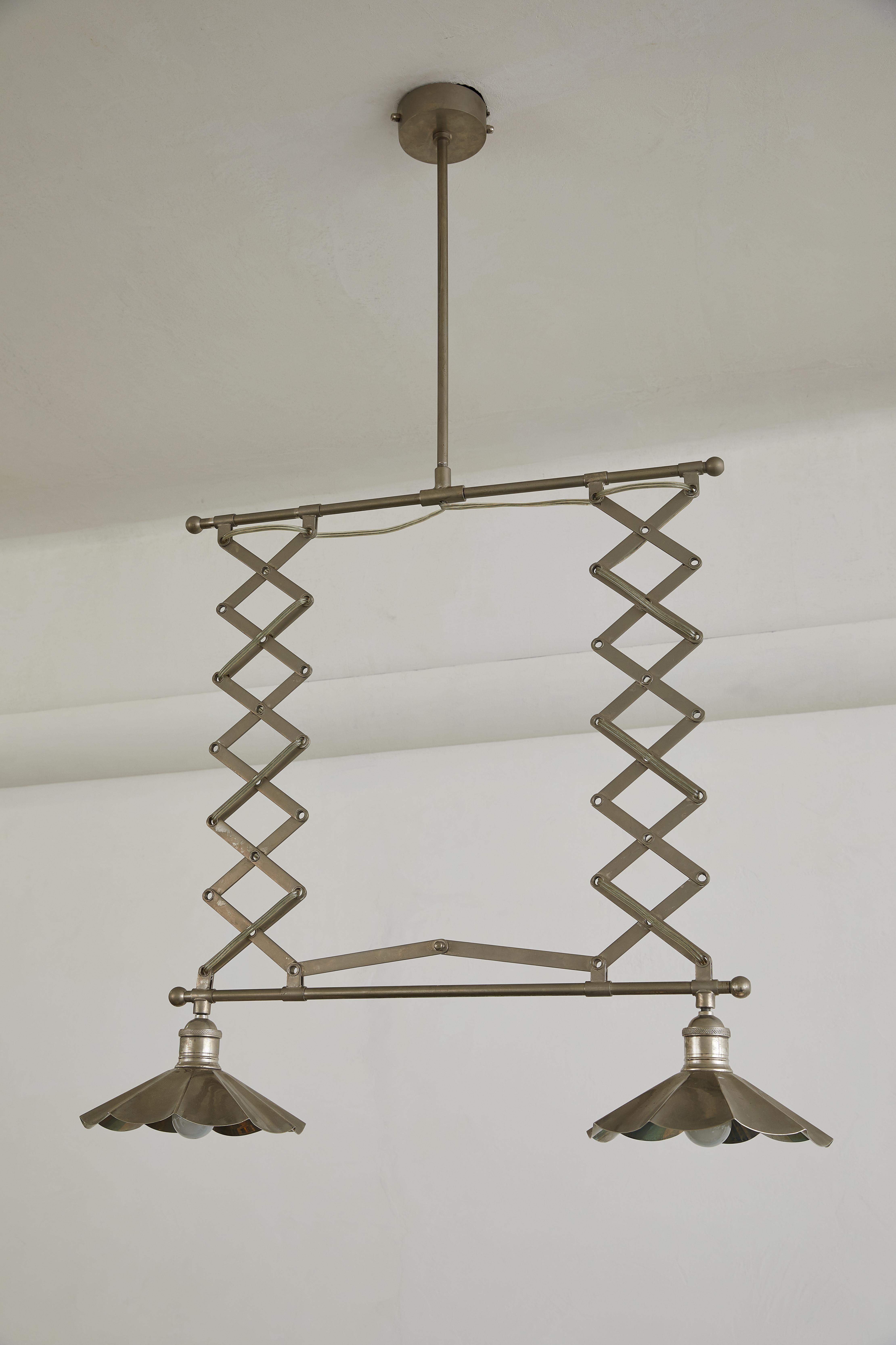 Questa elegante e regolabile lampada a sospensione a doppia fisarmonica Mid-Century Modern è un raffinato esempio di funzionalità industriale che incontra l'estetica contemporanea. Dotato di bracci cromati estensibili, l'apparecchio si regola da 32