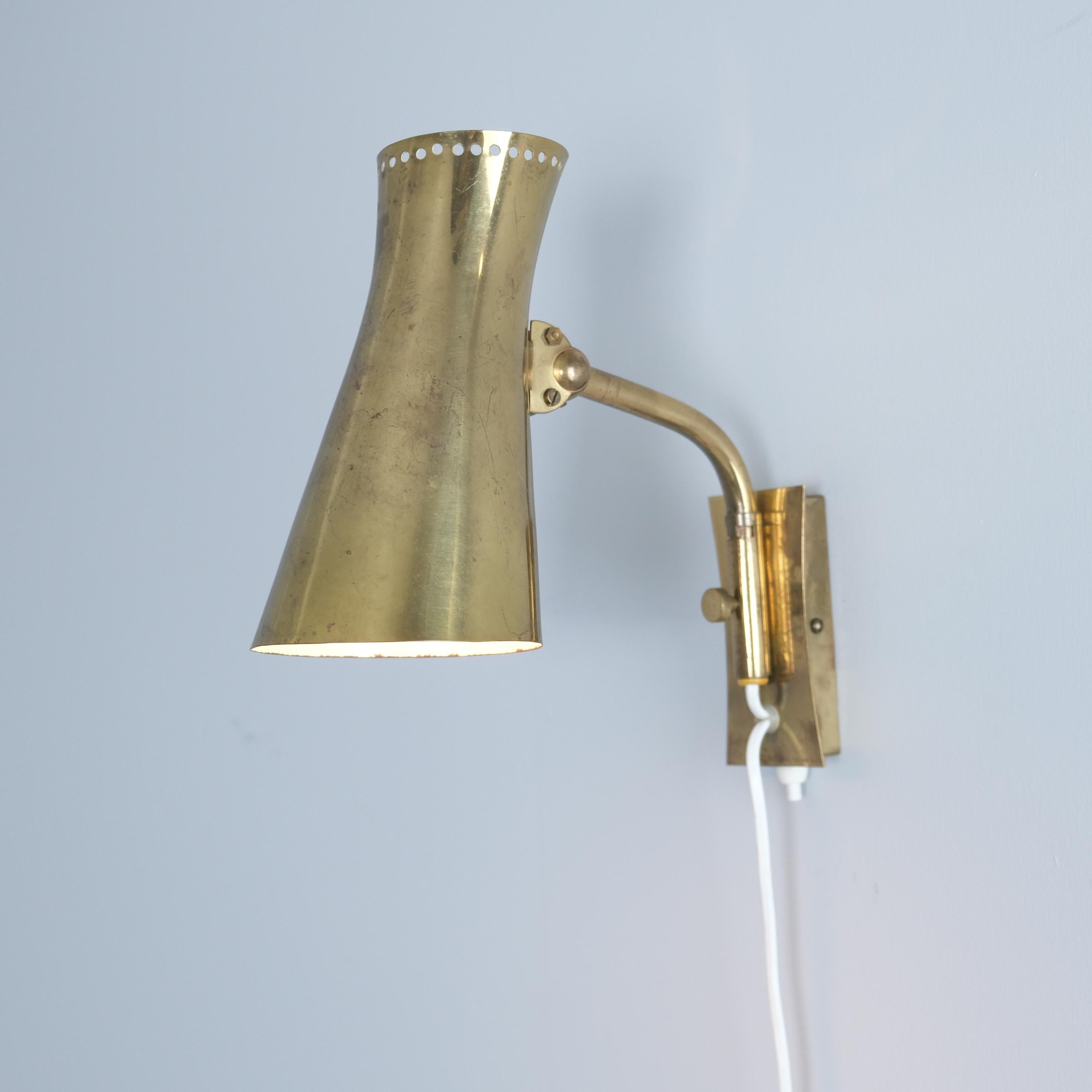Una lampada da parete regolabile in ottone pieno della metà del secolo scorso realizzata da Itsu in Finlandia negli anni '50. Il modello della lampada è AI 16 e ha un design particolare con un paralume in ottone regolabile che può essere sollevato e
