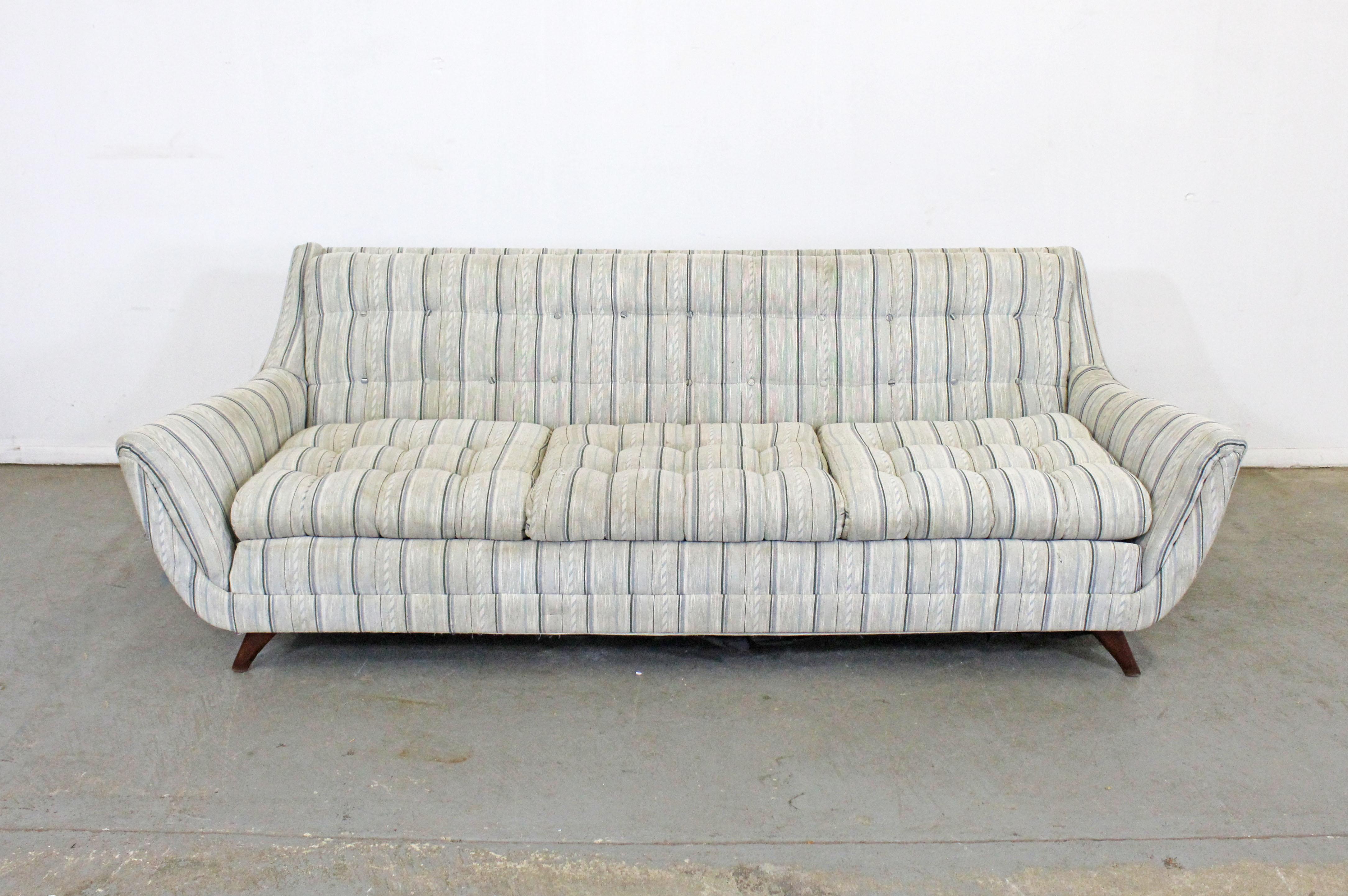Offered is a gorgeous vintage Mid-Century Modern sofa, in the style of Adrian Pearsall for Bassett 'Prestige'. Features a tufted backs, 3 removable seat cushions, and sits on splayed walnut legs. In decent condition with noticeable age wear - needs