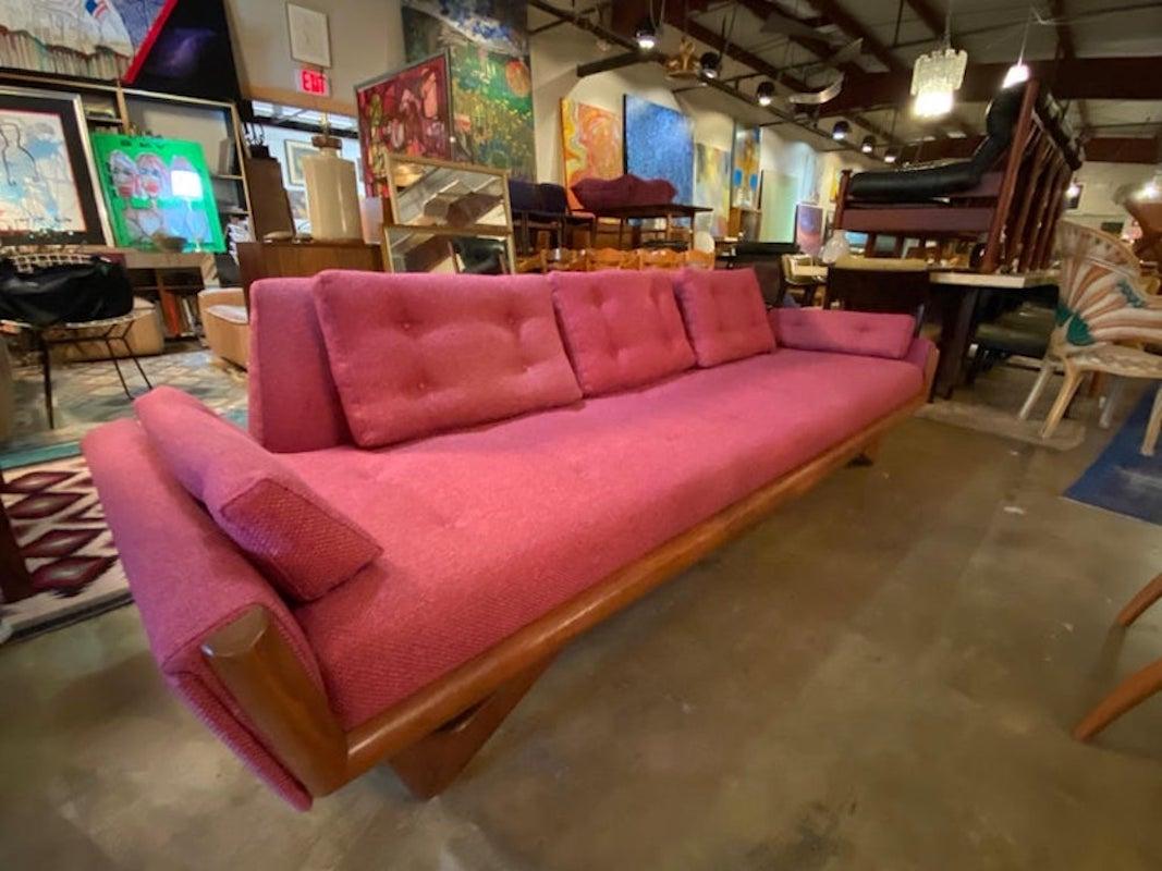 Mid-Century Modern Gondola sofa by Adrian Pearsall with a walnut base has been reupholstered in a magenta colored fabric and is in good condition. This large vintage sofa measures 98