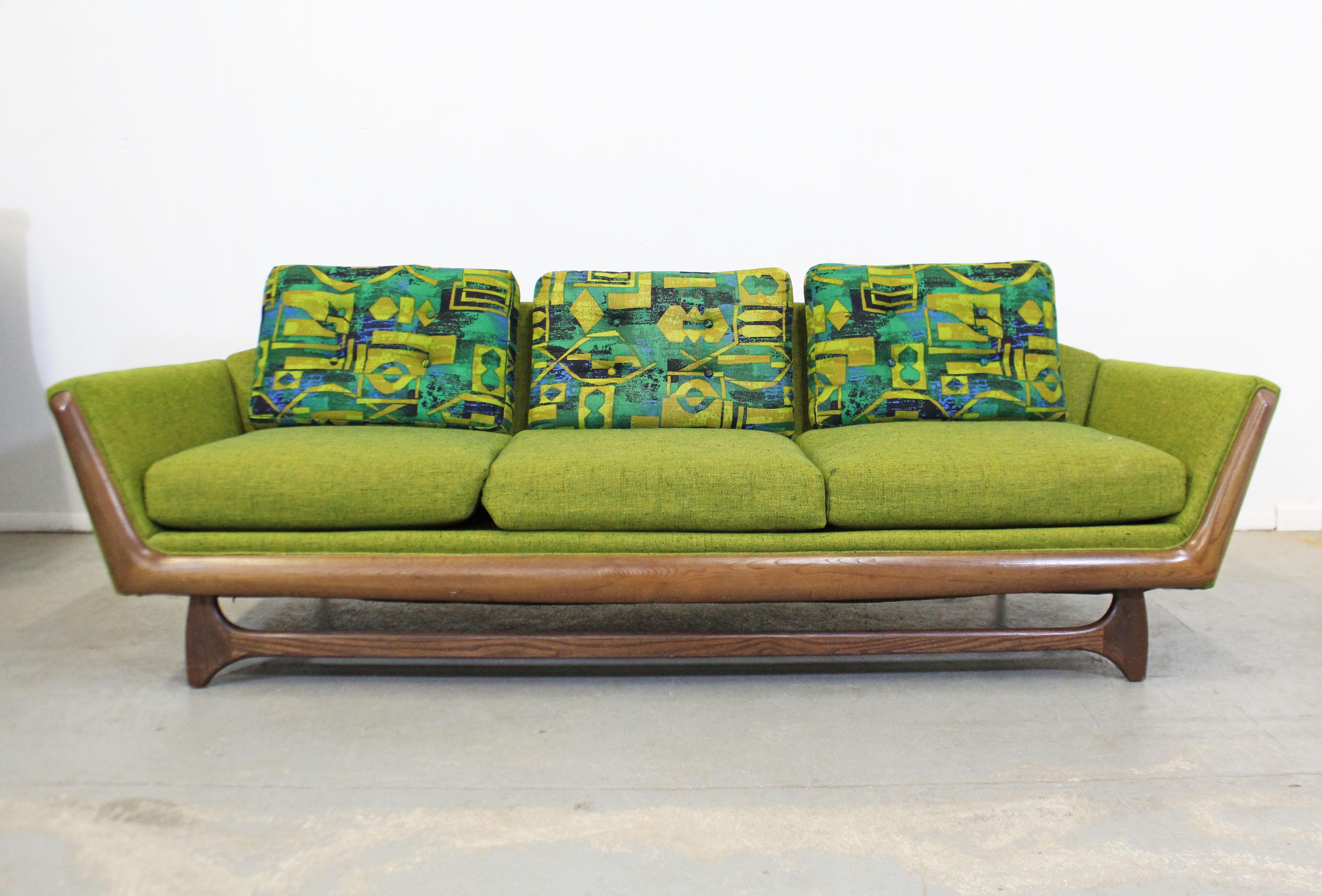 Offered is a gorgeous Mid-Century Modern sofa similar to the style of Adrian Pearsall. Absolutely incredible lines on this sofa. Features a sculpted wooden base, original green upholstery with three removable blue/green back cushions with a funky