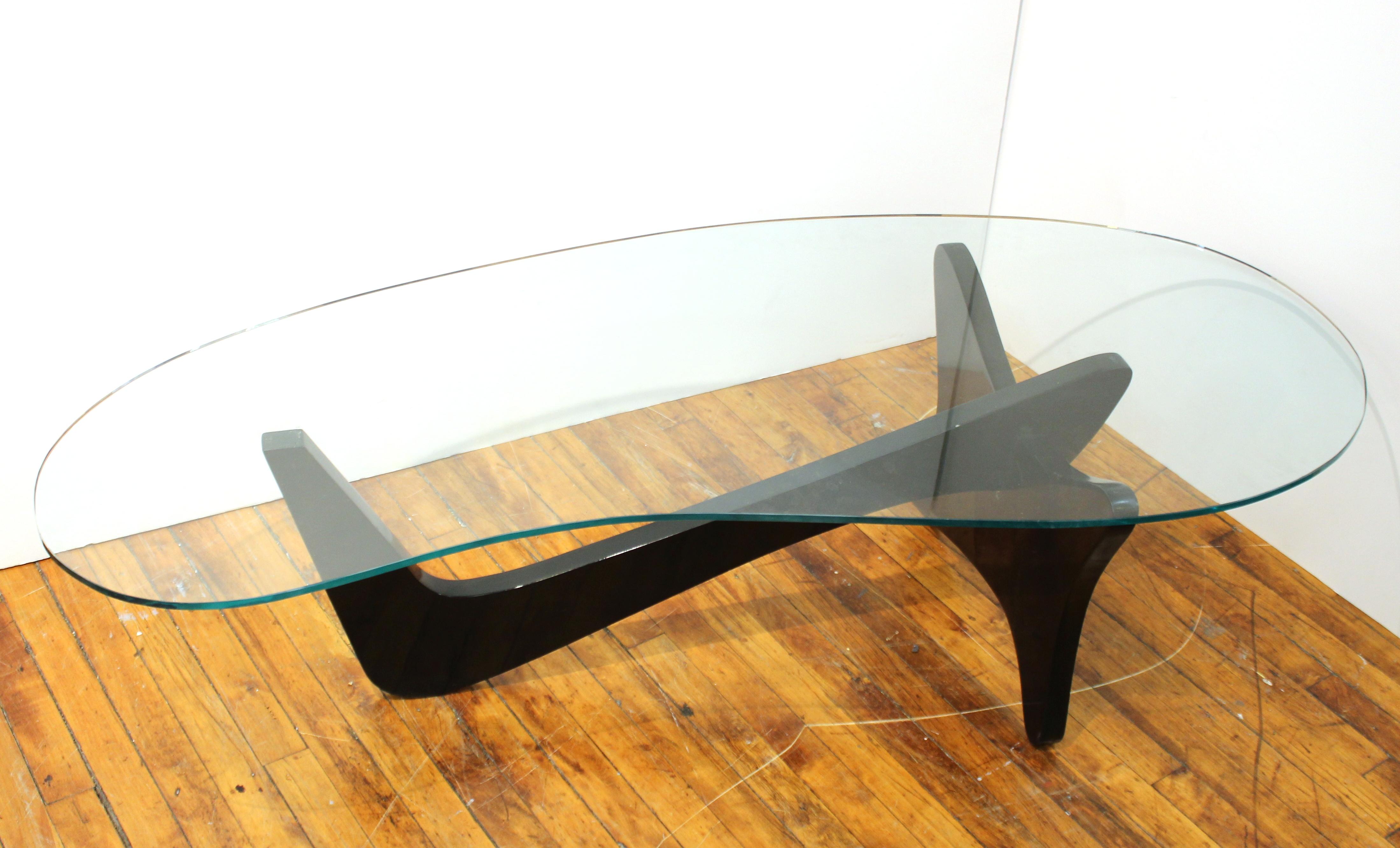 American Mid-Century Modern 'Airplane' coffee or cocktail table in black lacquered carved wood with a kidney-shaped glass top. The piece is in the same vein as the designs of Isamu Noguchi and dates from the 1950s. In great vintage condition.