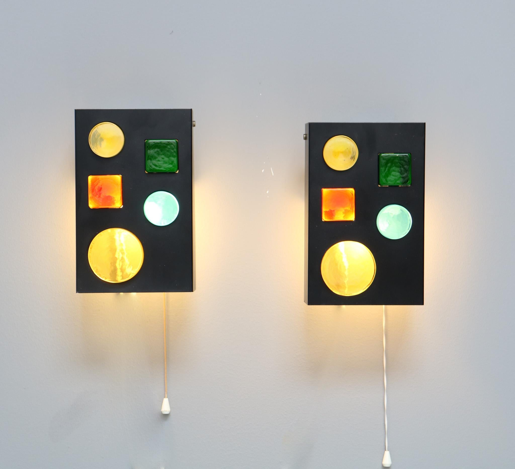 Stunning and rare pair of Mid-Century Modern wall lights objects.
Design by Raak Amsterdam.
Model: Alchemy 1968.
Striking Dutch design from the 1960s.
Original black lacquered metal frames with original multi-colored Murano glass.
With original pull