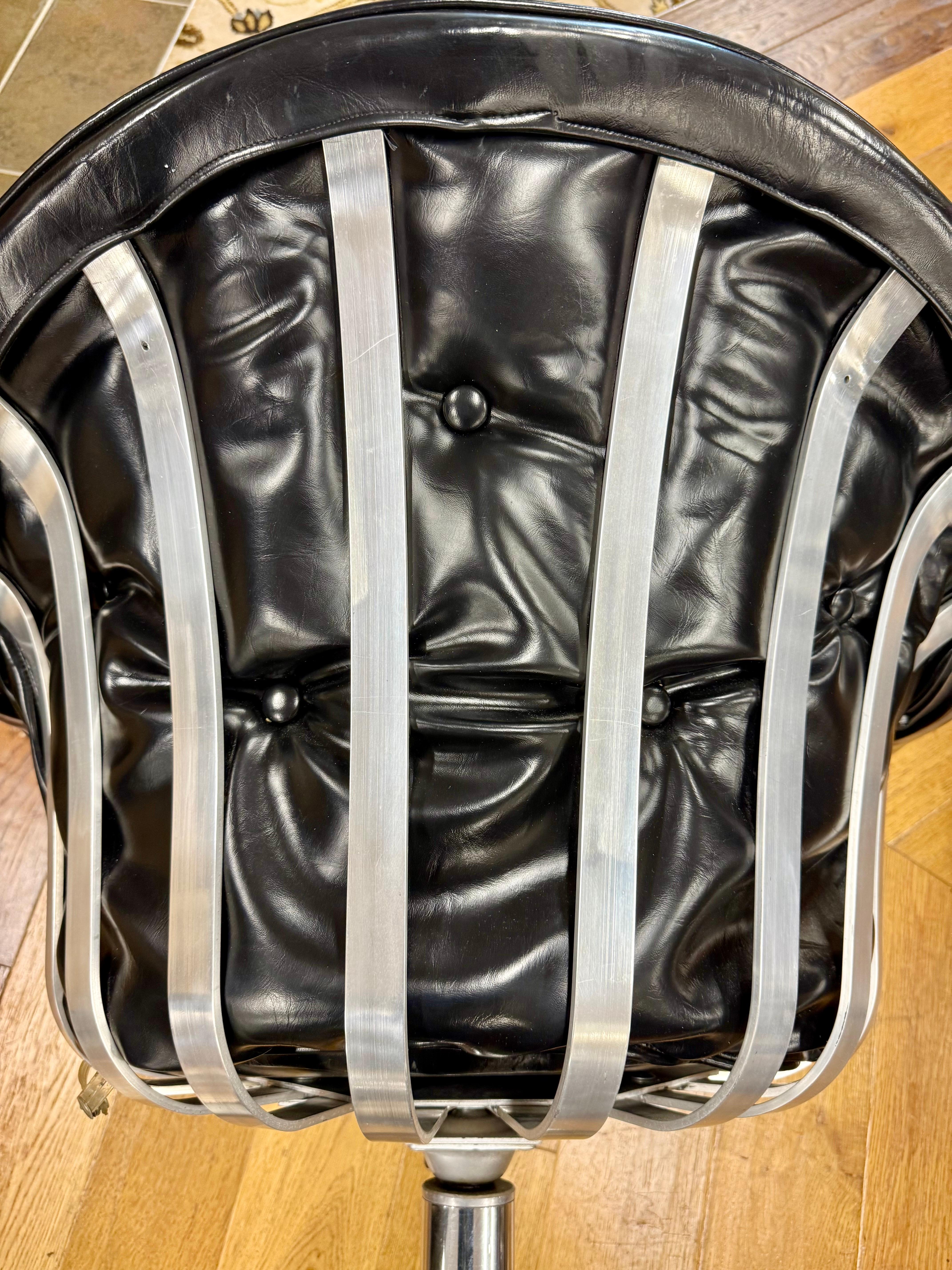Iconic pair of mid century aluminum and leather scoop chairs by Herbert Saiger for Russell Woodard, circa early 1970's.  The pair swivel 360 degrees and note the original black leather is still in great shape thanks to the original, and only, owner.