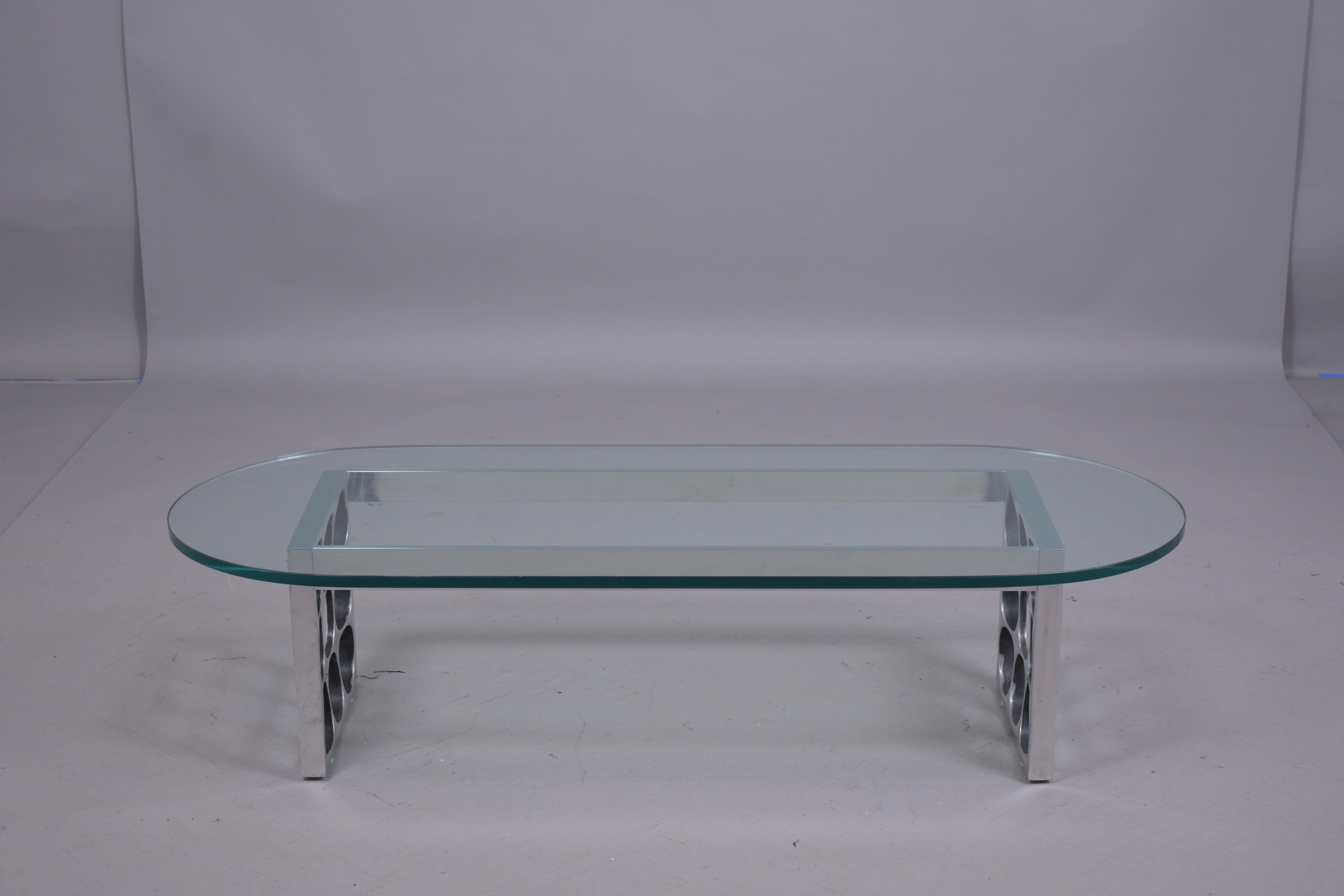A mid-century modern metal glass coffee table in great condition that has been professionally restored by our team of expert craftsmen. This racetrack glass top table features a half-inch beveled oval clear glass in a good condition that sits on an