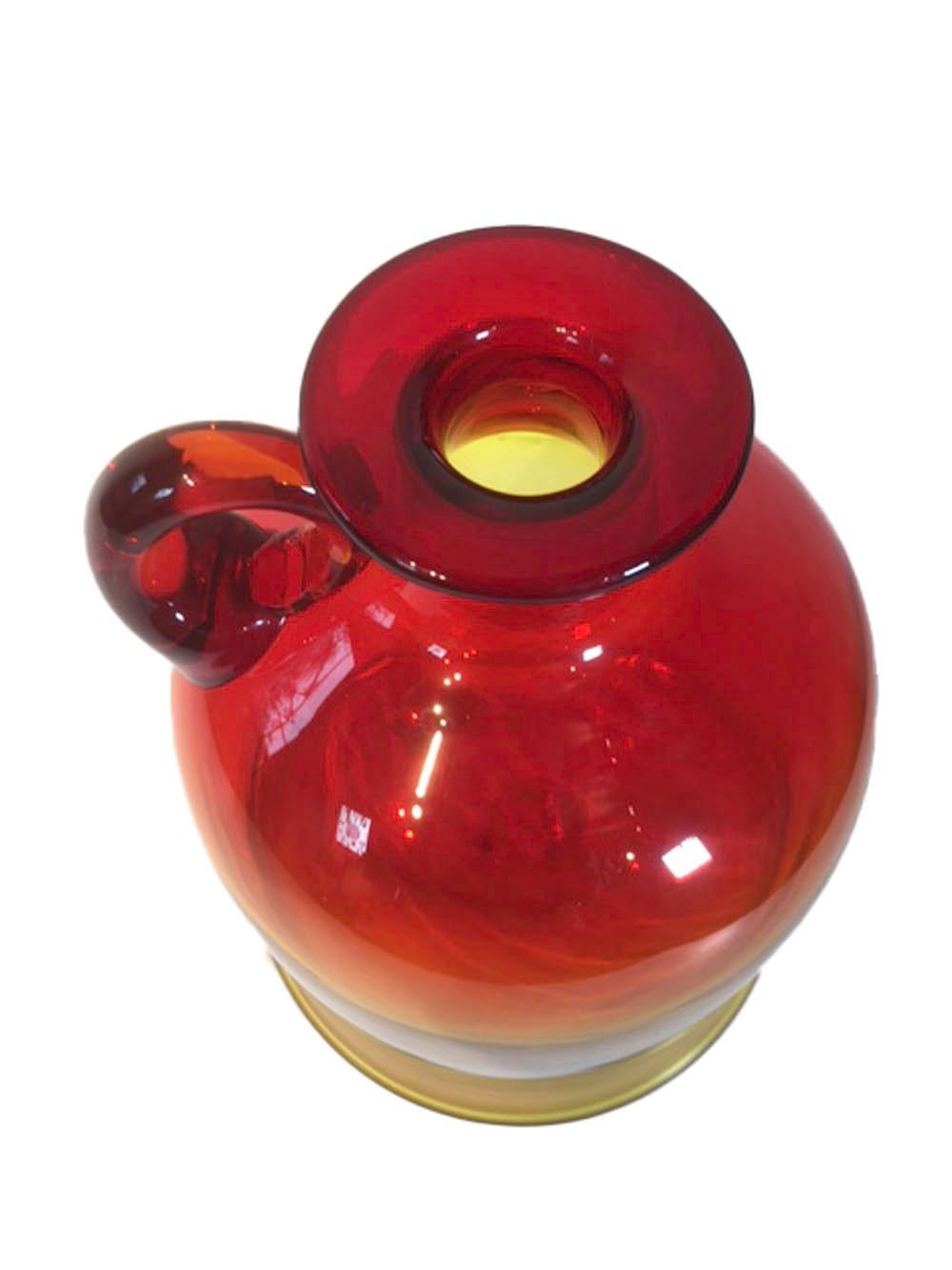 Mid-20th century Blenko glass moonshine jug in amberina - large size of rounded bell form having a single applied loop handle below the flared mouth and an out-turned rim at the base. Vibrant yellow base graduating through orange to red at the top.
