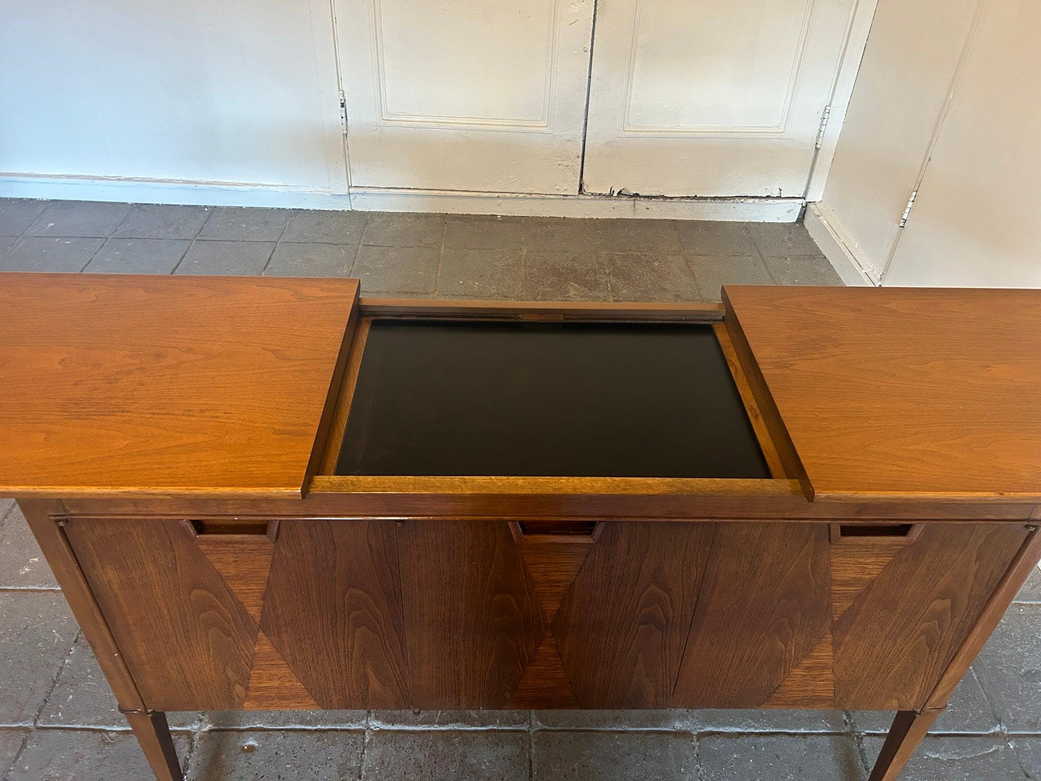 Mid-Century Modern rolling bar cart made by the Mount Airy Furniture Co. Of North Carolina - Janus Collection sold by John Stuart. Expanding Walnut top to reveal Black Laminate in center. Walnut bar cart with contrasting Triangle walnut inlays on