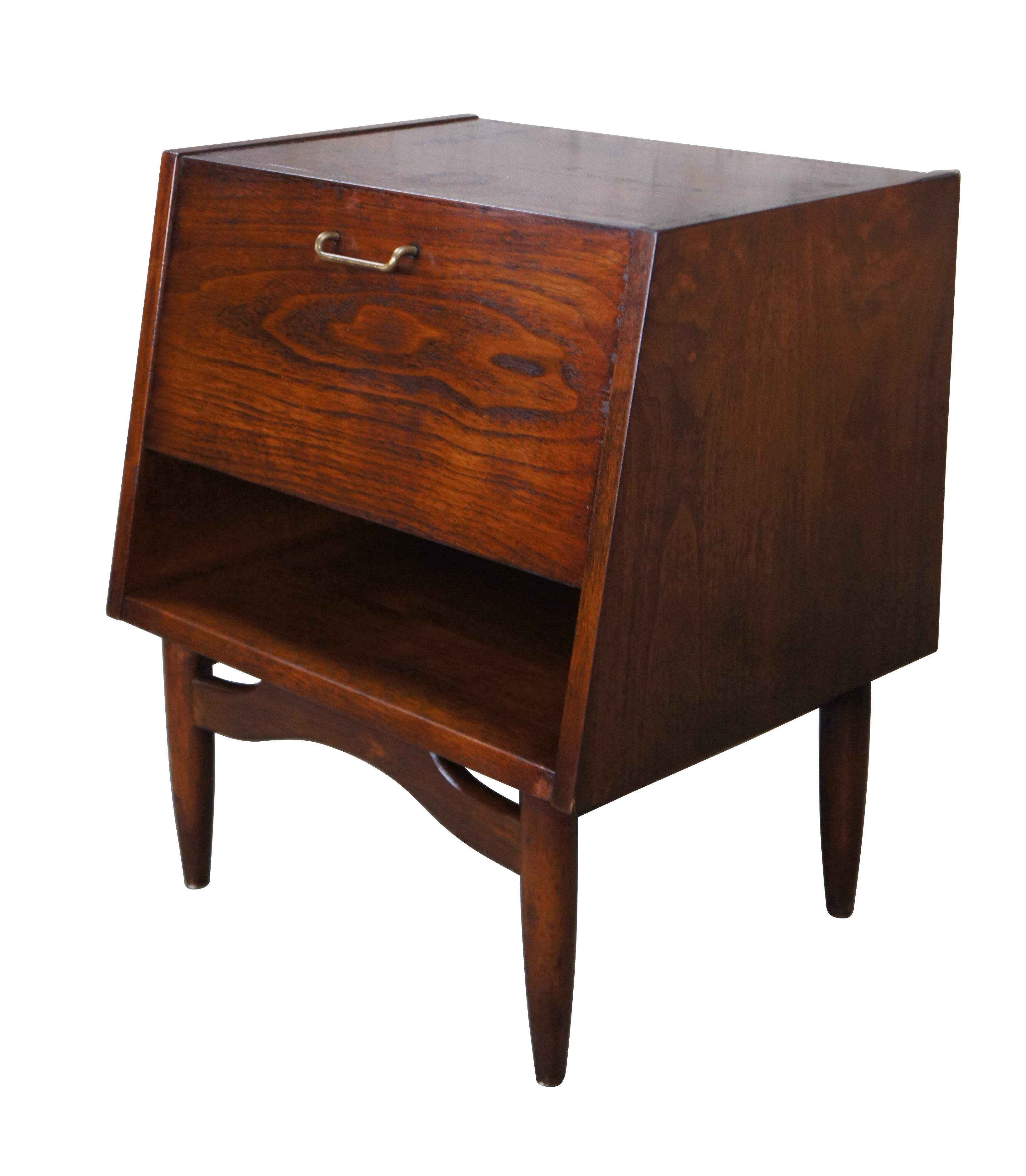 Mid century modern American of Martinsville nightstand or nite table.  Made of walnut featuring drop front with brass hardware, lower cubbie and tapered legs.

Dimensions:
22