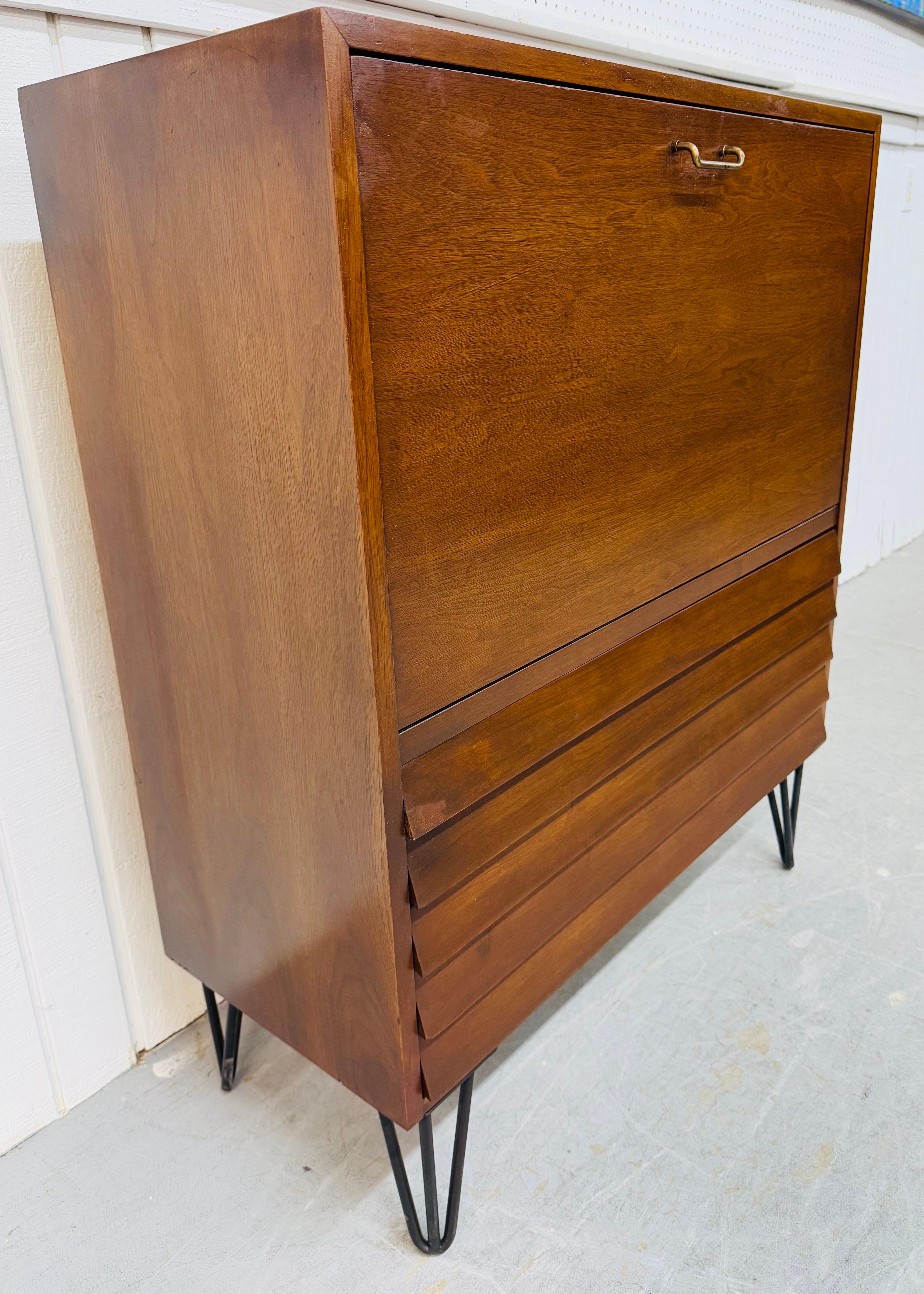 Diese Auflistung ist für einen Mid-Century Modern American of Martinsville Dania Walnut Storage Cabinet. Mit einem geradlinigen Design, einer Klapptür, die sich zum Stauraum öffnet, zwei unteren Schubladen, schwarzen Haarnadelbeinen und einer