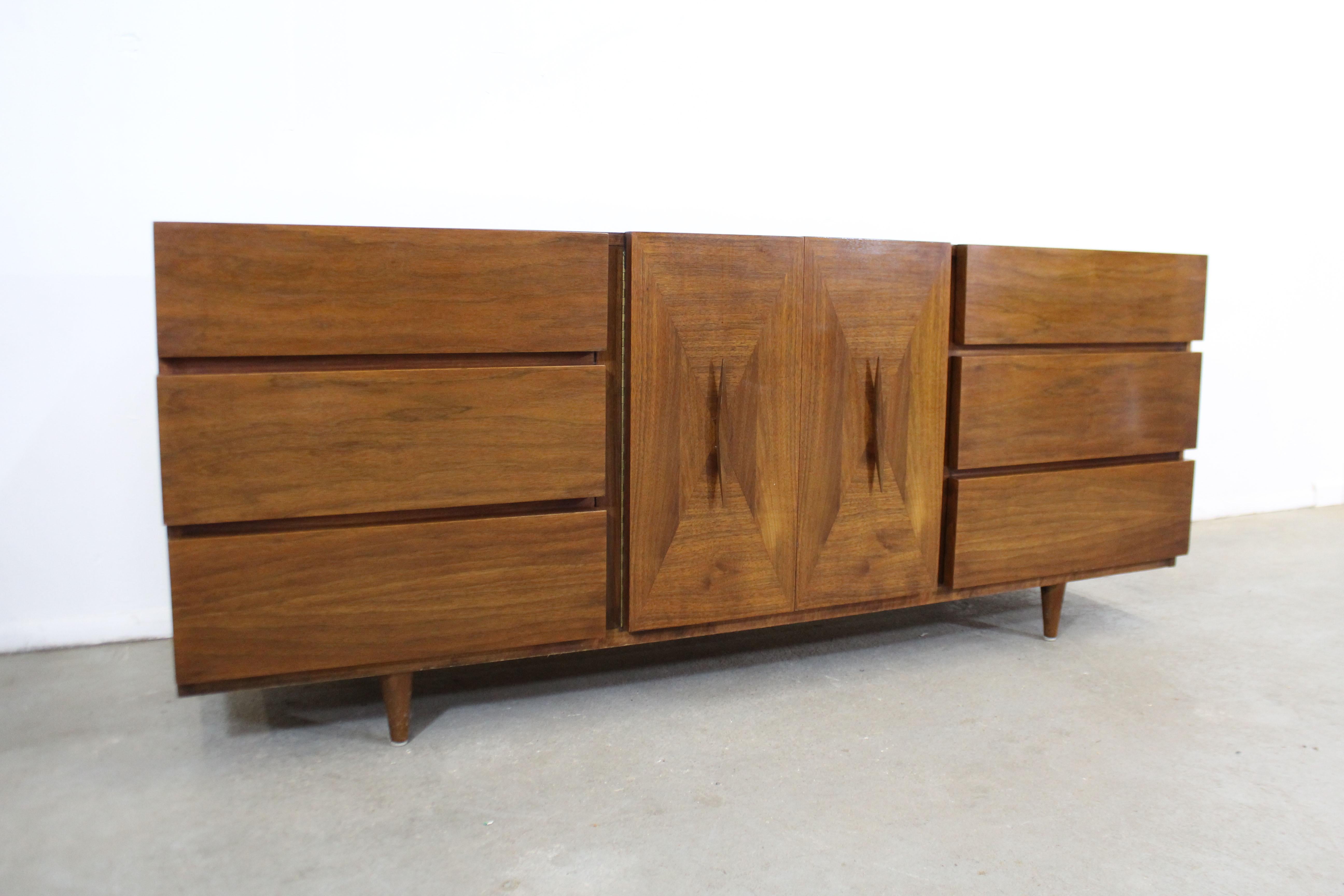 Offered is a Mid-Century Modern credenza made of walnut by American of Martinsville. Features beautifully parqueted doors with sculpted handles. Includes nine dovetailed drawers, three behind the doors. It is in good condition with some surface