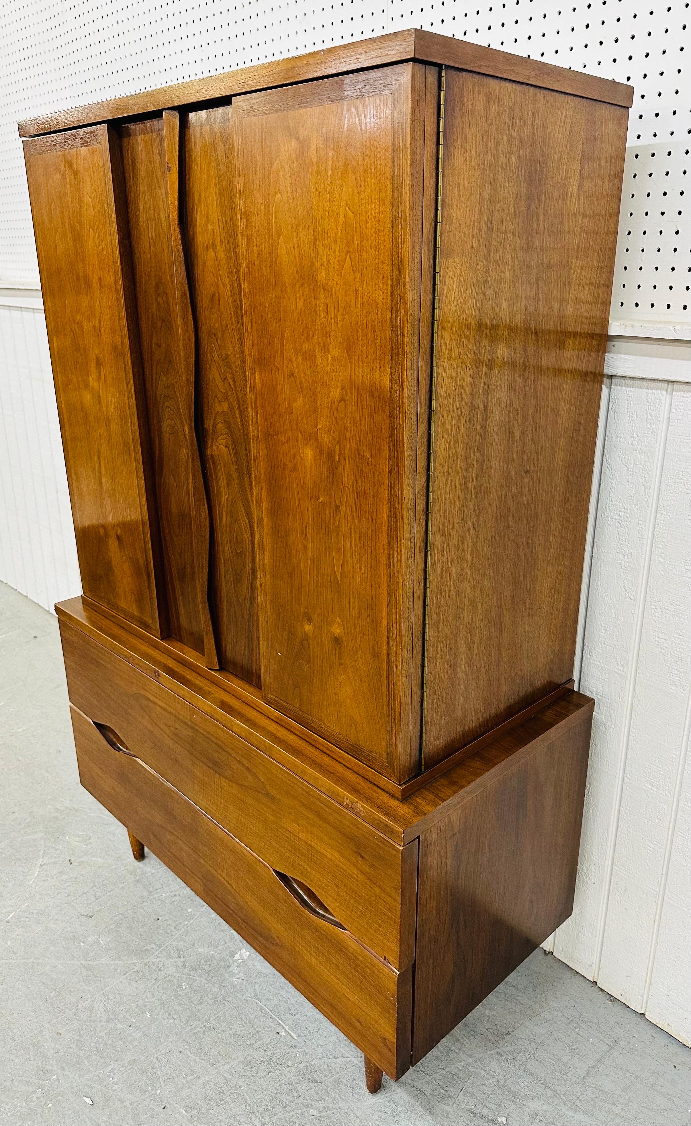 This listing is for a Mid-Century Modern American of Martinsville Walnut Armoire. Featuring a straight line design, two large doors that open up to hidden storage space, separated storage compartments, three interior drawers, two larger drawers at