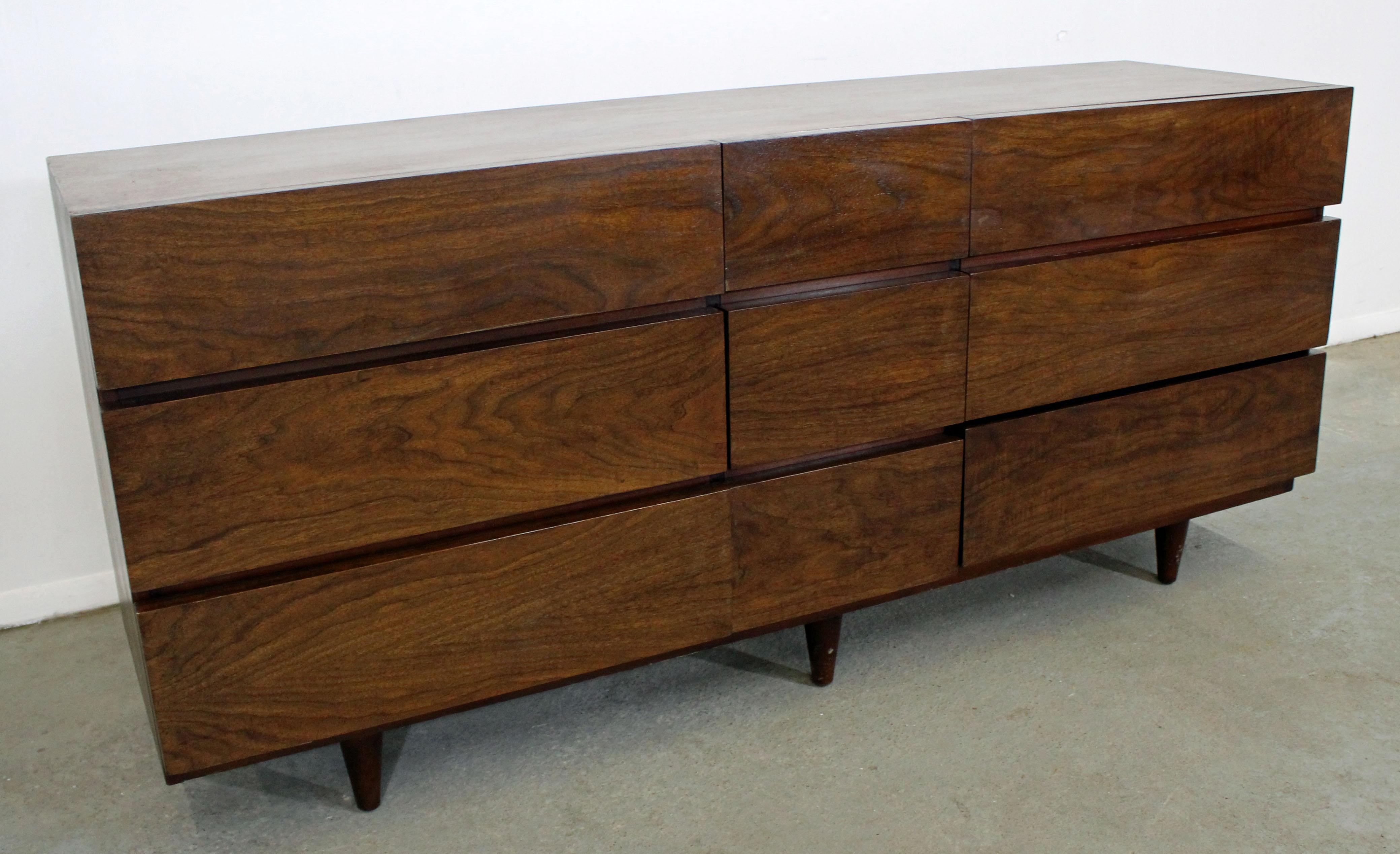 Offered is a Mid-Century Modern walnut credenza/dresser, made by American of Martinsville. It is made of walnut with nine drawers. It is in excellent condition for its age, shows minor signs of wear (has been refinished, slight surface