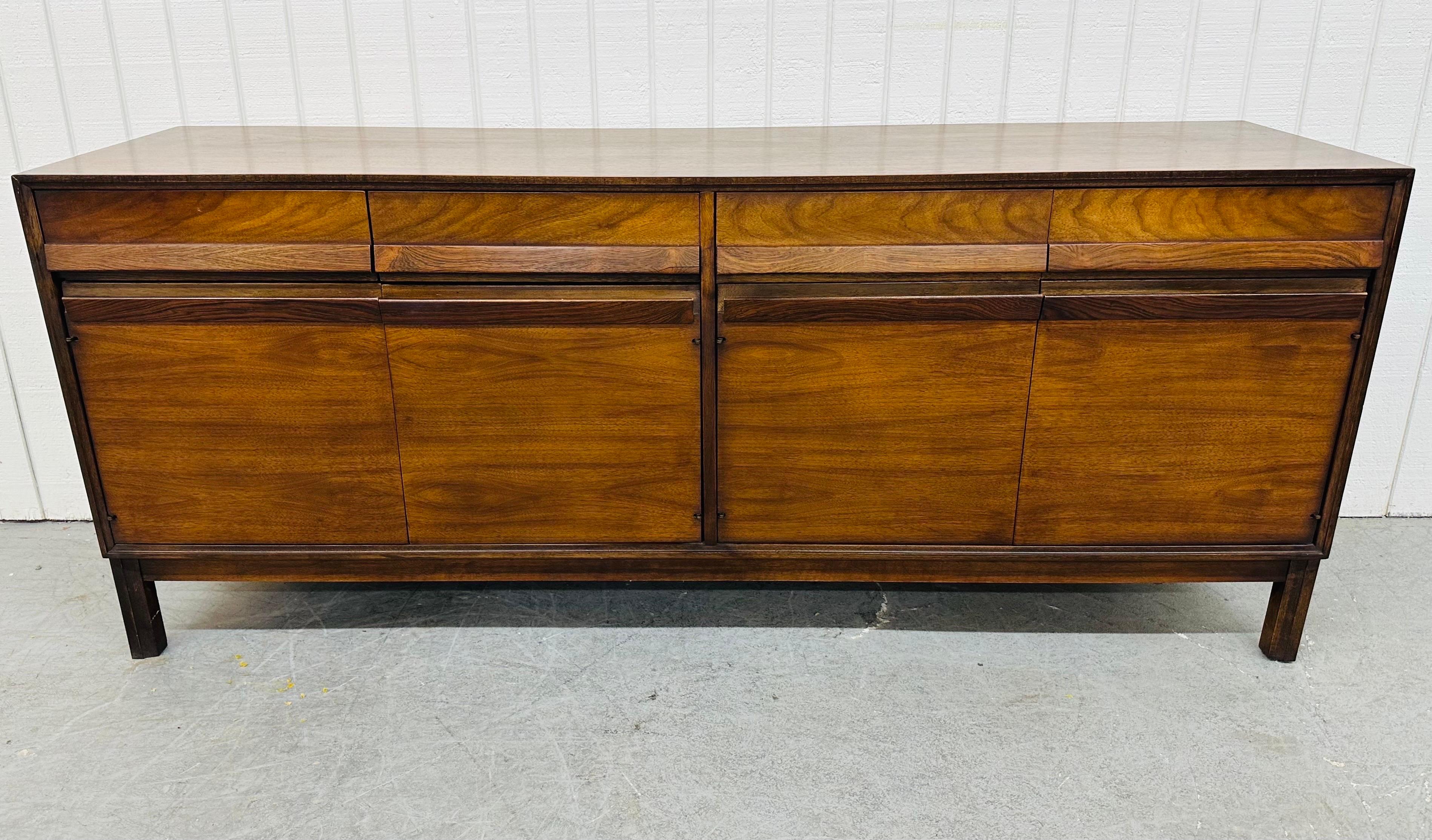 This listing is for a Mid-Century Modern American of Martinsville Walnut Sideboard. Featuring a straight line design, four small drawers with rosewood pulls along the top, two doors on the left with rosewood pulls that open up to storage space, two