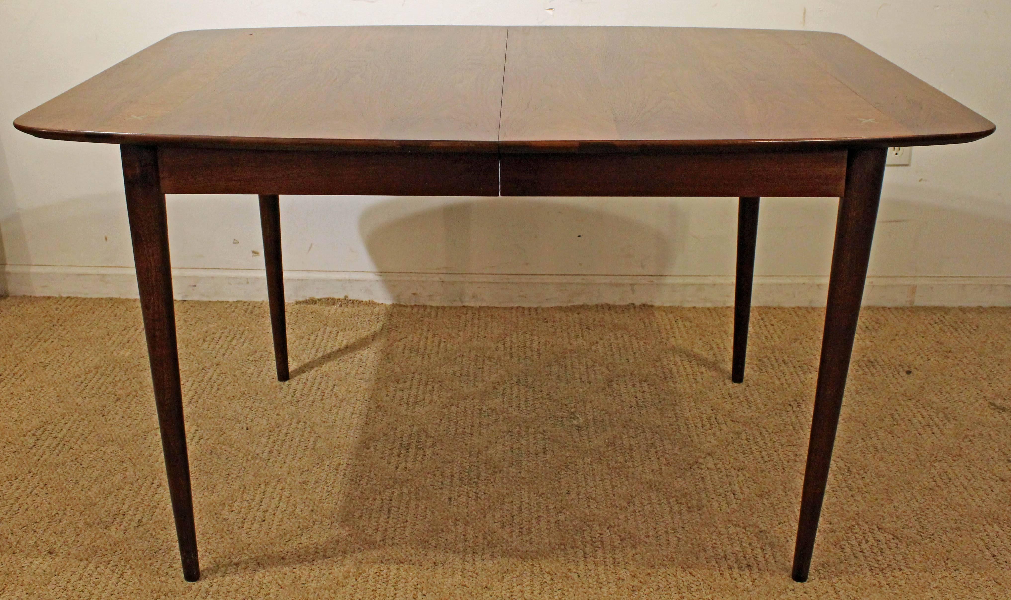 Offered is a Mid-Century Modern extendable dining table, made by American of Martinsville. Features beautiful walnut and inlay bands across each end along with the infamous aluminium X's on the corners. Includes two 12