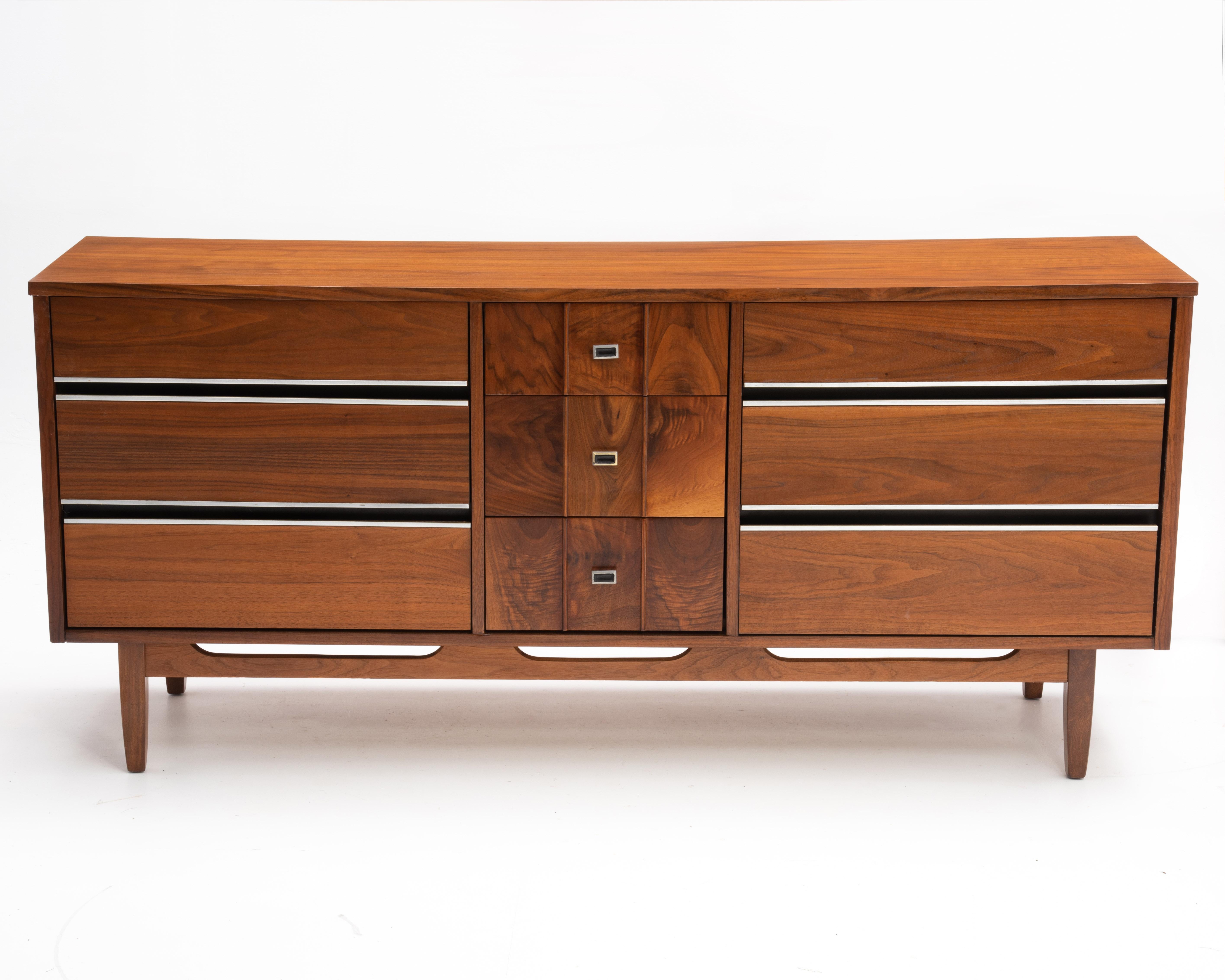 A fantastic Mid Century Modern walnut dresser, unmarked and by an unknown maker. The center three drawers feature nine panels with highly figured walnut, three panels per drawer.. The six side drawers have chrome drawer pulls. We also have the