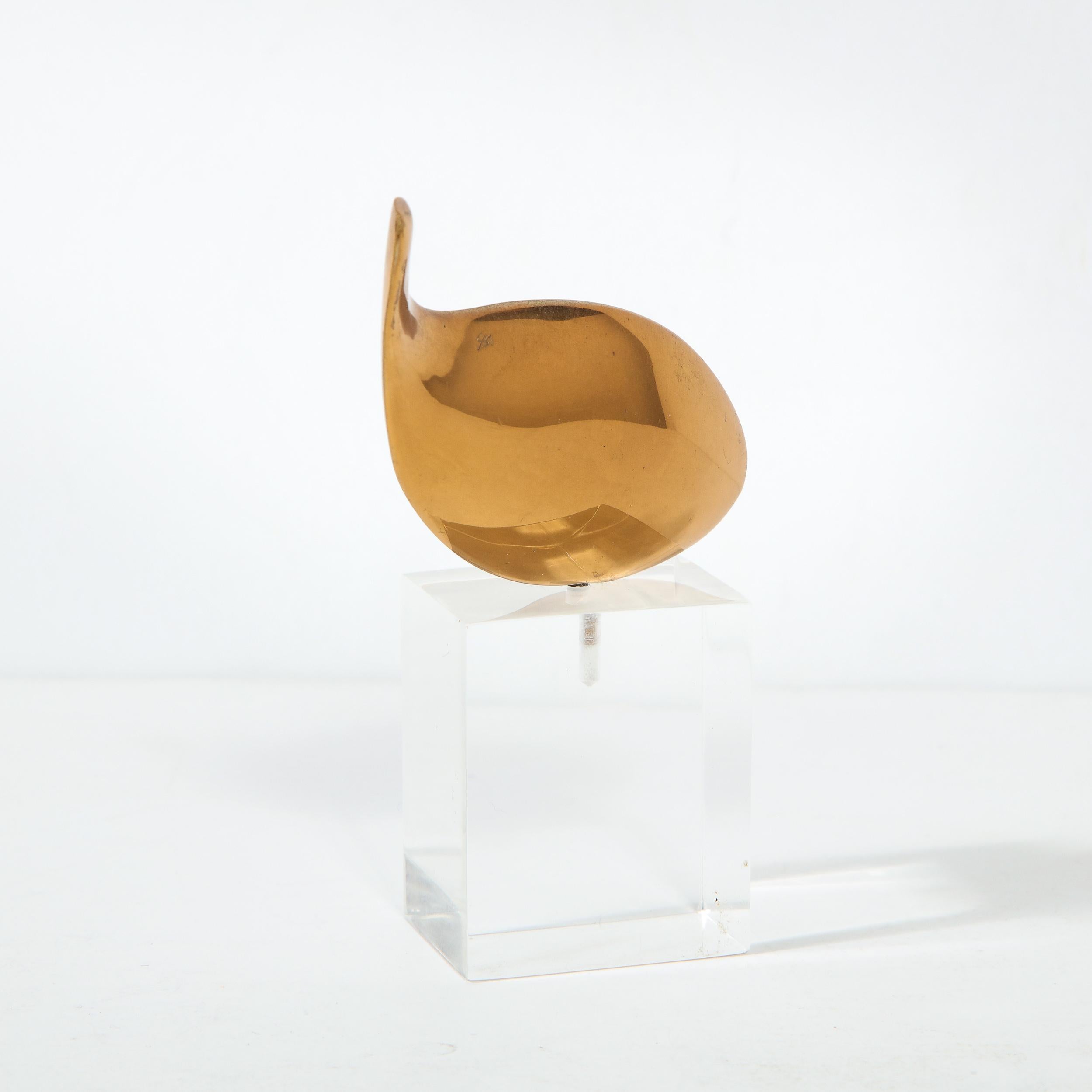 This stunning and sophisticated Mid Century Modern sculpture was realized in the United States circa 1960. It features an amorphic form- an elongated ovoid with a tapered tail resembling an abstracted fish- presented on a volumetric rectangular