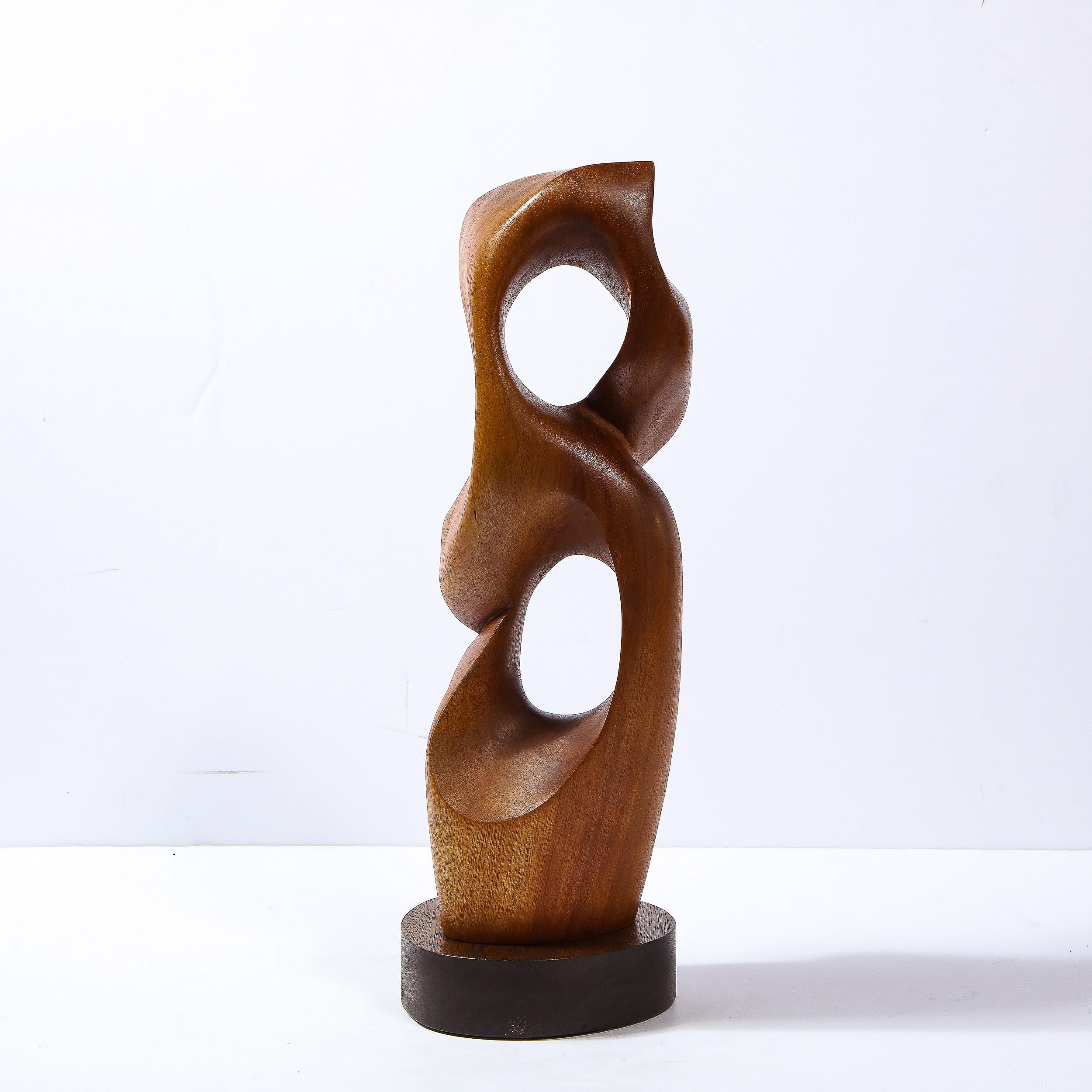This sophisticated and refined Mid-Century Modern sculpture was realized in the United States circa 1960. It features a curvilinear amorphic body consisting of a panoply of interlacing forms. Composed of handrubbed walnut, the piece offers two