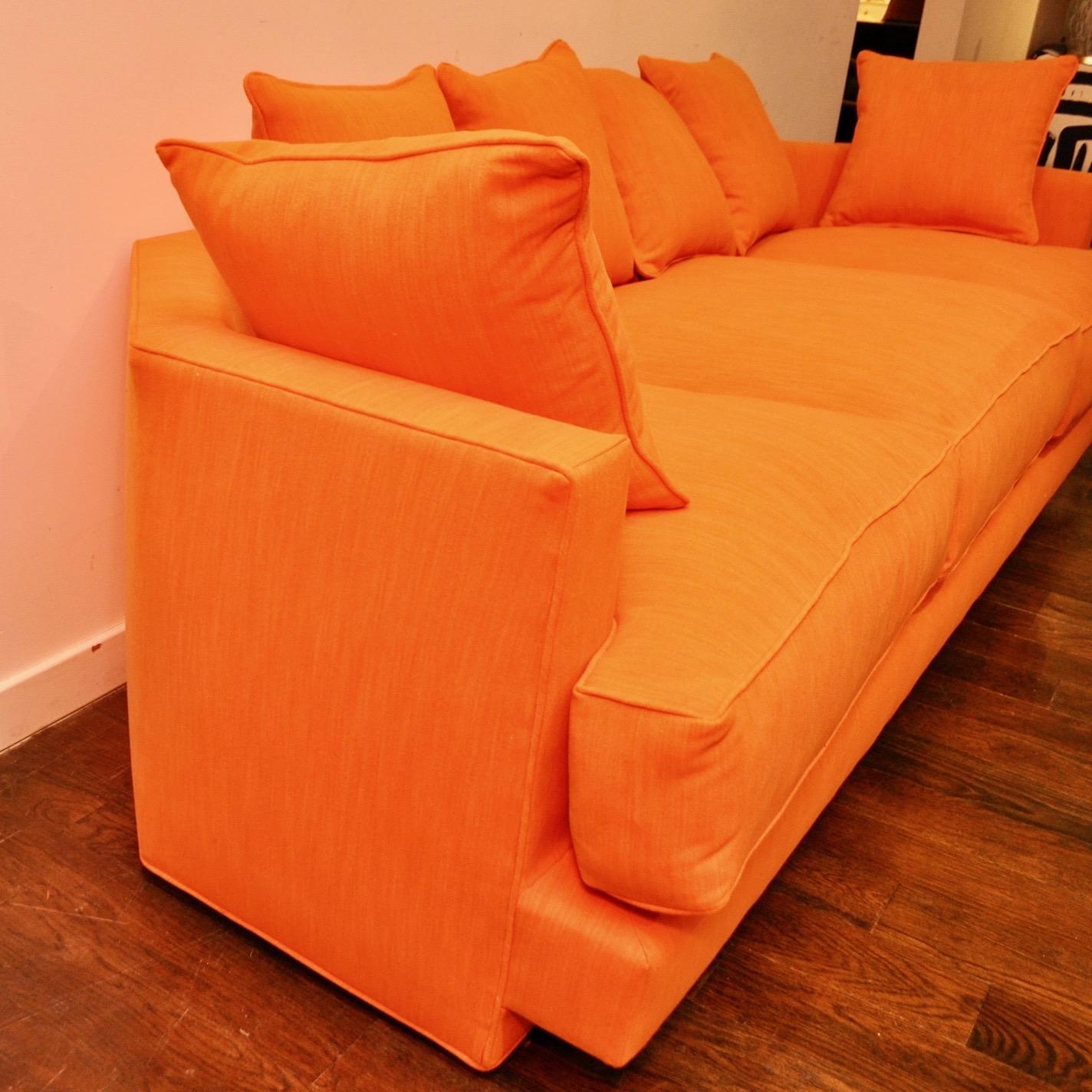1970s era sofa, possibly custom made, with a unique angled back. Newly reupholstered in an orange cotton velvet with thick down-filled cushions. Thanks to its interesting shape, this piece can easily float out from the wall.