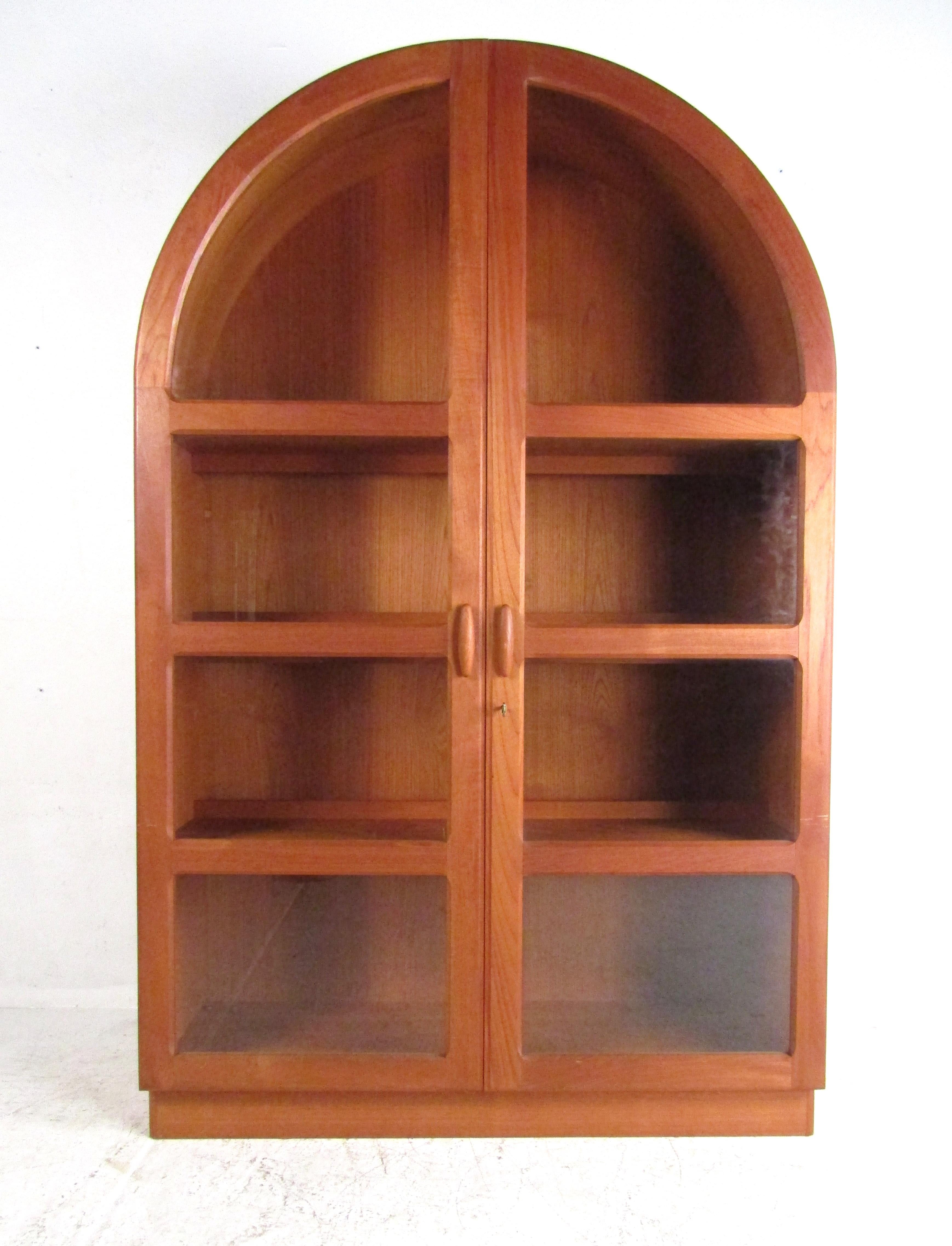 This impressive vintage modern teak wardrobe/armoire features a unique arched top with two large cabinet doors that open to unveil four teak wood shelves. A wonderful Danish design that ensures plenty of room for storage and makes for an ideal space