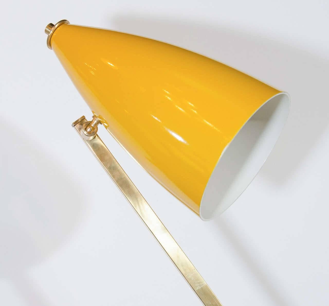 Mid-Century Modern Italian architectural floor lamp. Features asymmetrical frame with geometric arm design in a brass. Has adjustable lamp shades in vibrant primary red and yellow. The shades have enameled finishes in different, yet complimenting