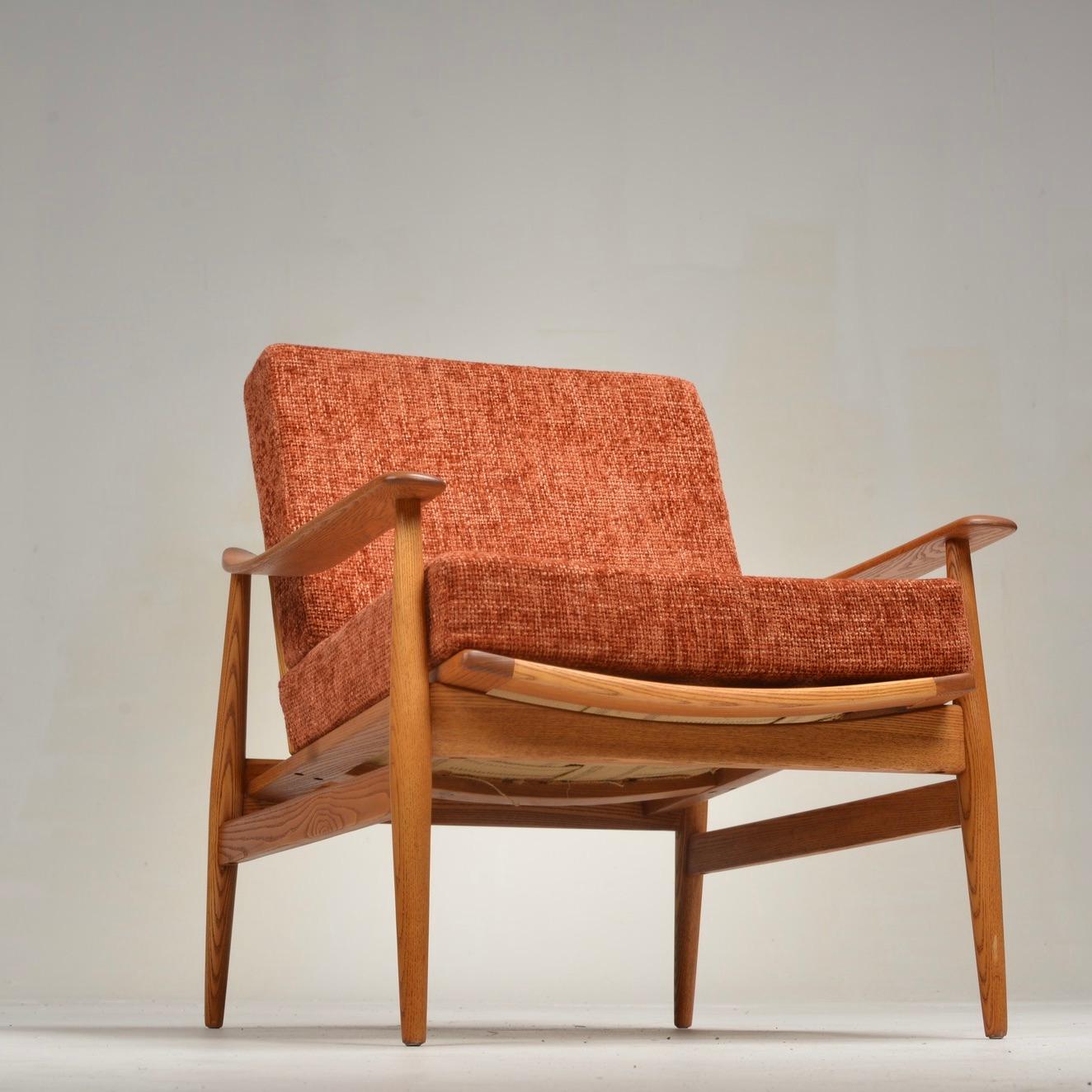 Beautiful 1970's / mid-century modern arm chair. Recently reupholstered, this solid ash chair is sleek and minimal, featuring a slatted back, slightly curved arm rests and an angular silhouette. The upholstery webbing was recently replaced for