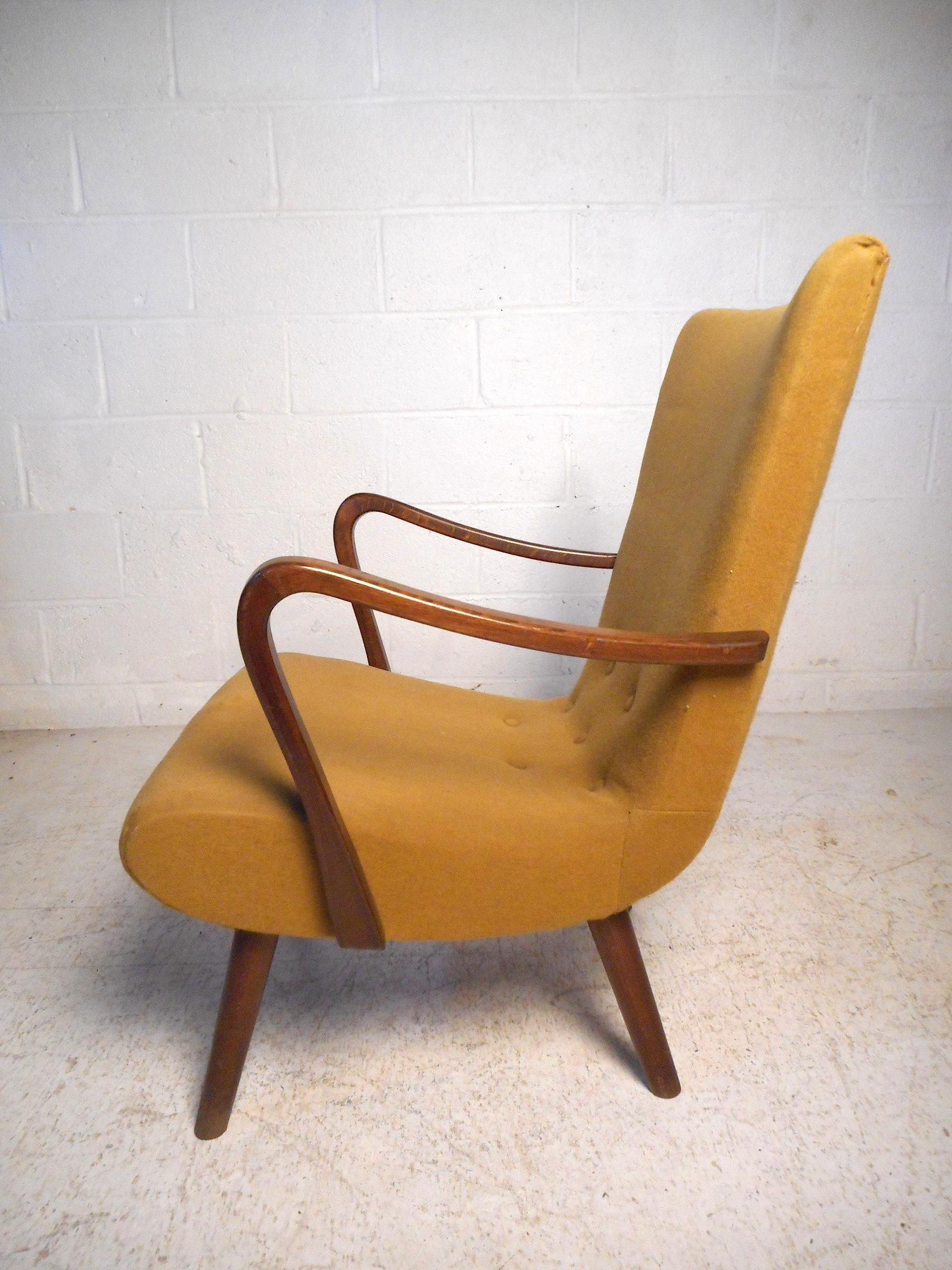 This impressive midcentury chair features vintage tufted upholstery, sculpted armrests, sturdy splayed legs, and a tall winged back. An impressive addition to any modern interior's seating arrangement. Please confirm item location with dealer (NJ or