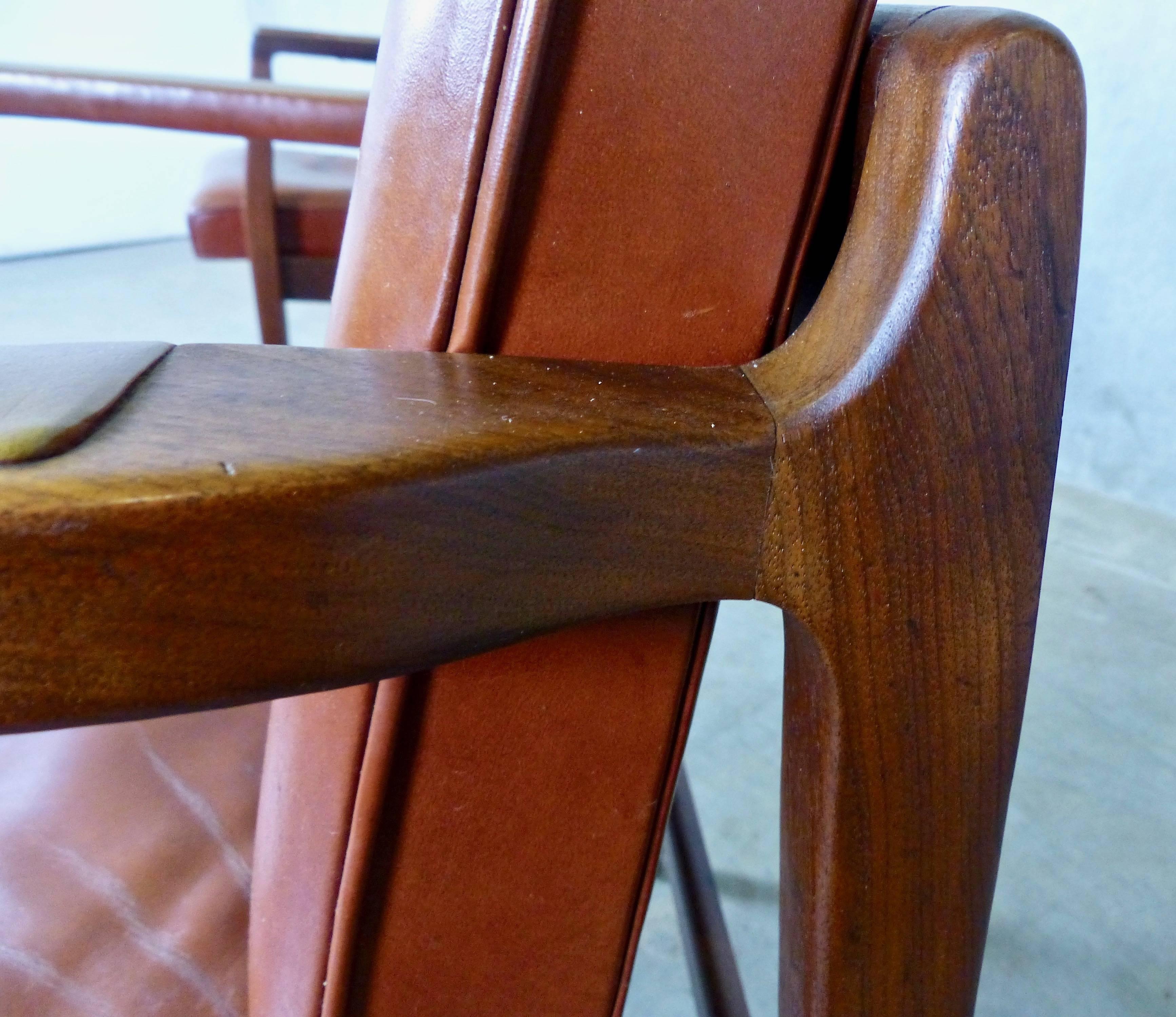 Matched pair of MCM armchairs in an amazing, on-trend rust color. 
Produced in the 1950s by the B.L. Marble Chair Company, which was founded in 1894 in Bedford, Iowa. 
Great style and cool leather armrest details in a solid wood-framed chair.