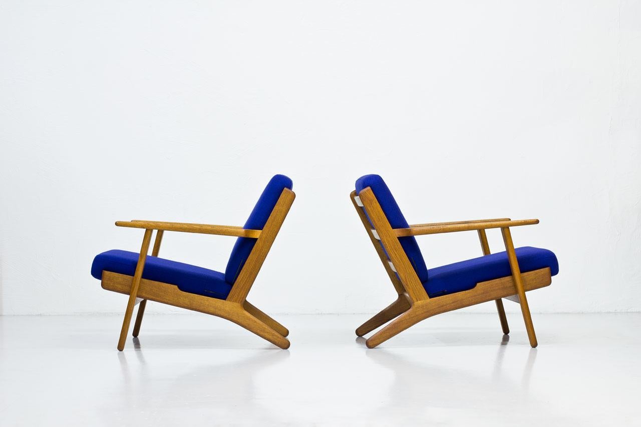 Pair of armchairs model “GE-290? designed by Hans J. Wegner. Produced by GETAMA, Gedsted in Denmark during the 1950s. Solid oak frame with large armrests. Loose cushions in a purple/ blue wool upholstery. New padding.
