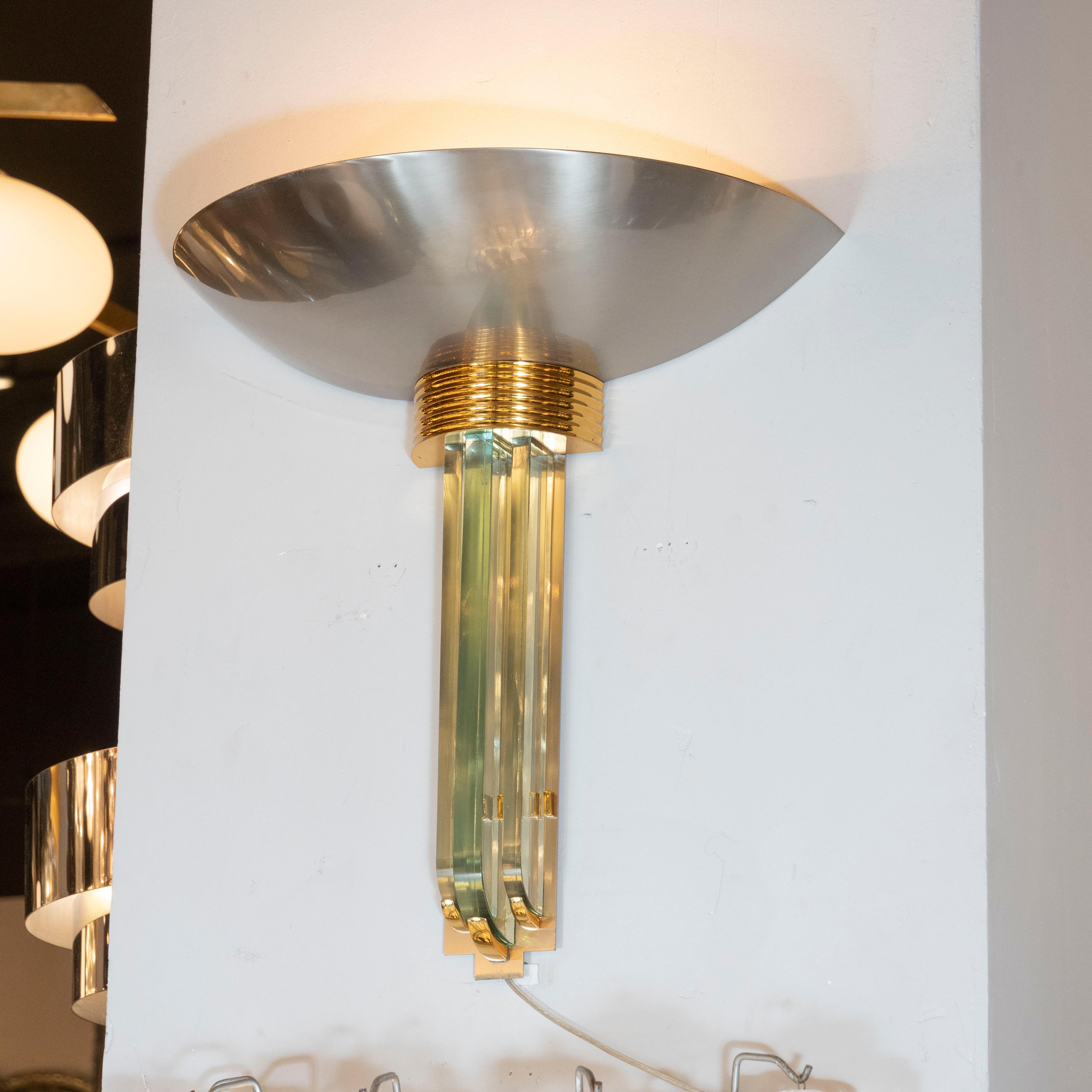 This bold and sophisticated contrasting metallic modernist sconce was realized in the United States, circa 1980. Inspired by the clean modernist lines of Art Deco, it features three streamlined glass forms secured with brass fittings; a fluted brass