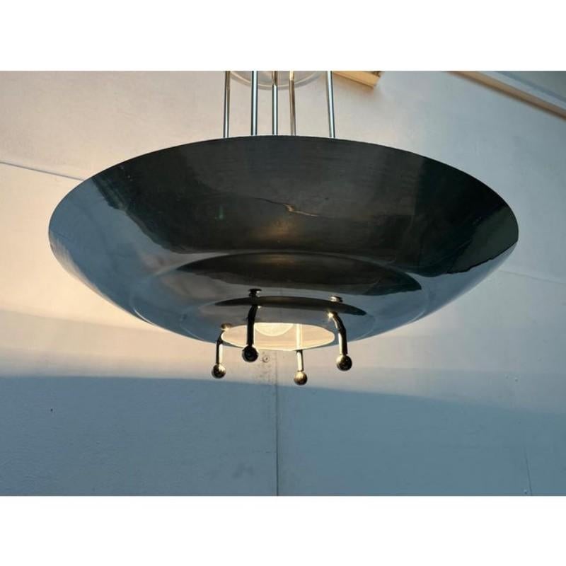 Imposing rod pendant light in the Art Deco style.

This ceiling floodlight is characterized by its elegant shade shape and reflective surface. The shade is formed by a large aluminum shell. There is a large hole in the middle. It is suspended on