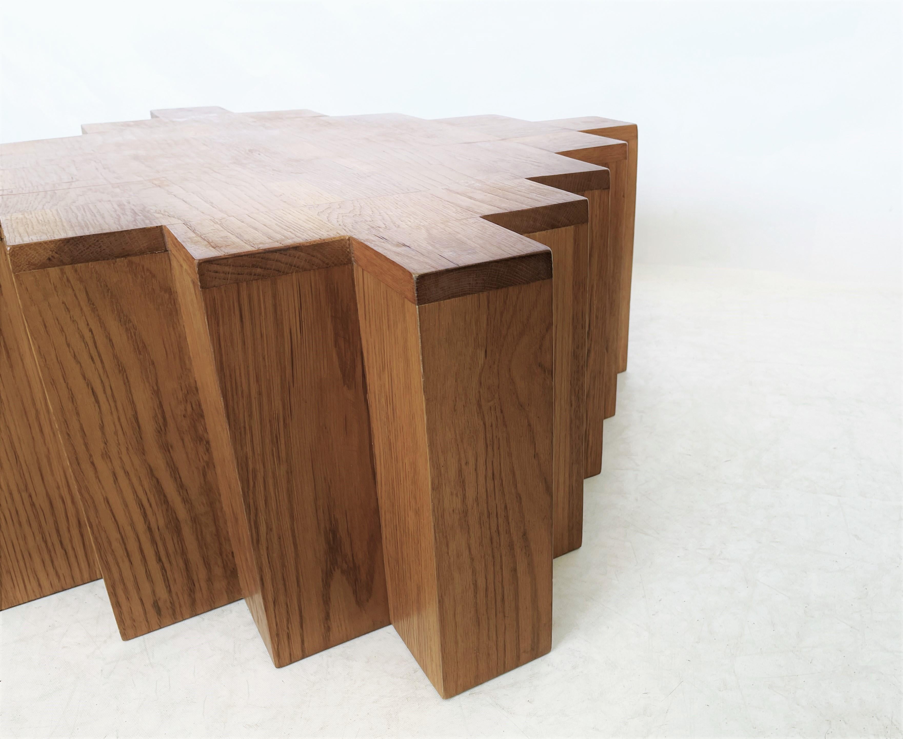 Table basse moderne et sculpturale. La forme géométrique forte du cube avec des coins symétriques répétitifs en retrait est accentuée par le grain distinctif et récurrent du bois de chêne naturel. De grandes proportions. Une patine incroyable. Il