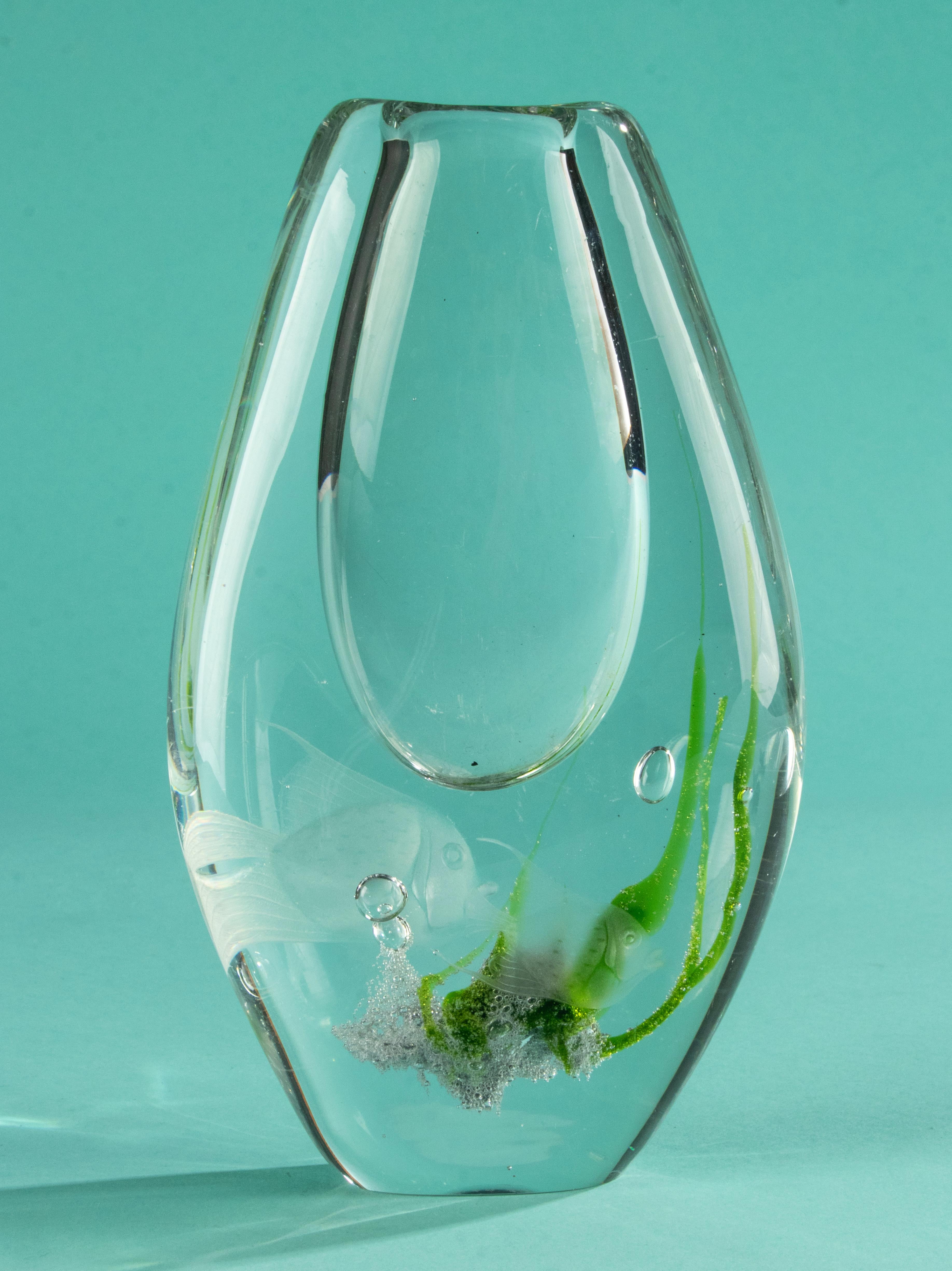 A beautiful art glass vase, made by the Swedish brand Kosta soda, designed by Vicke Lindstrand. 
The vase is made of thick layers glass with clear green inclusions and etched fish on both sides. 
The vase is in good condition. Signed on the bottom.