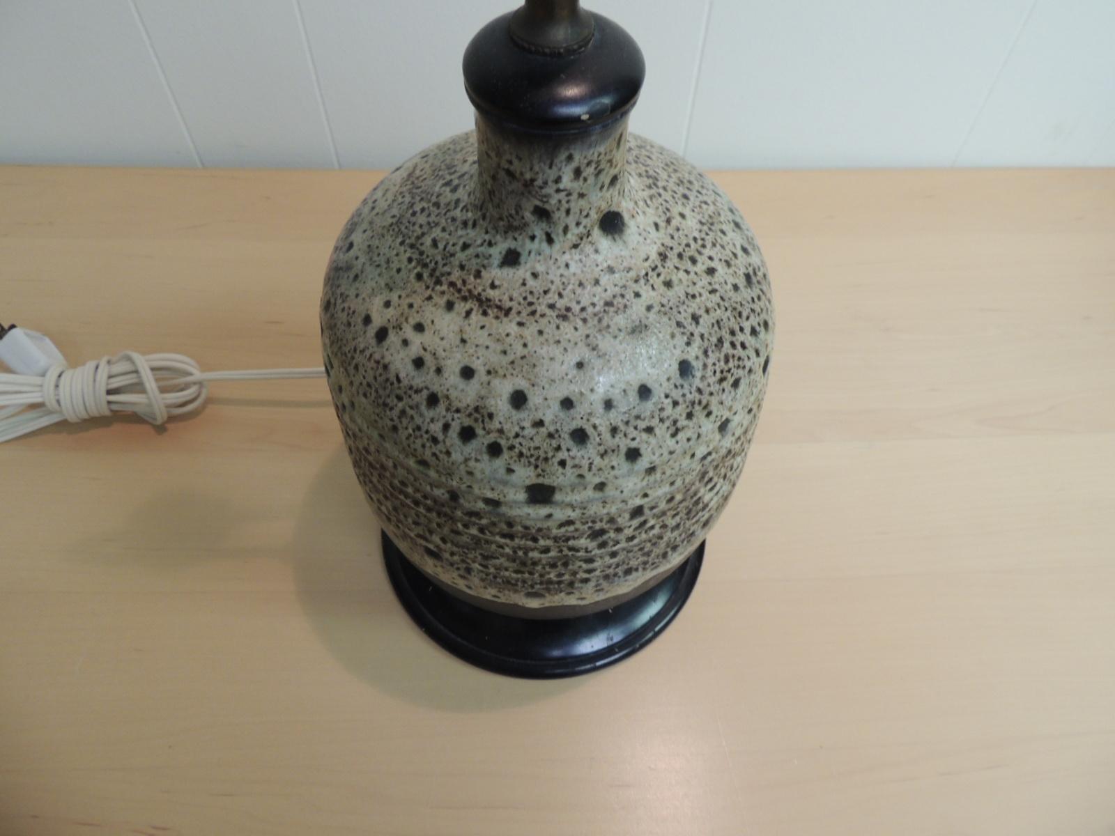Mid-Century Modern art pottery ceramic table lamp. Round textured spotted ceramic lamp, mounted on wood base and wood topper in a dark mahogany finish. Brass fittings. Includes harp. No shade.
Newly re-wired and three way