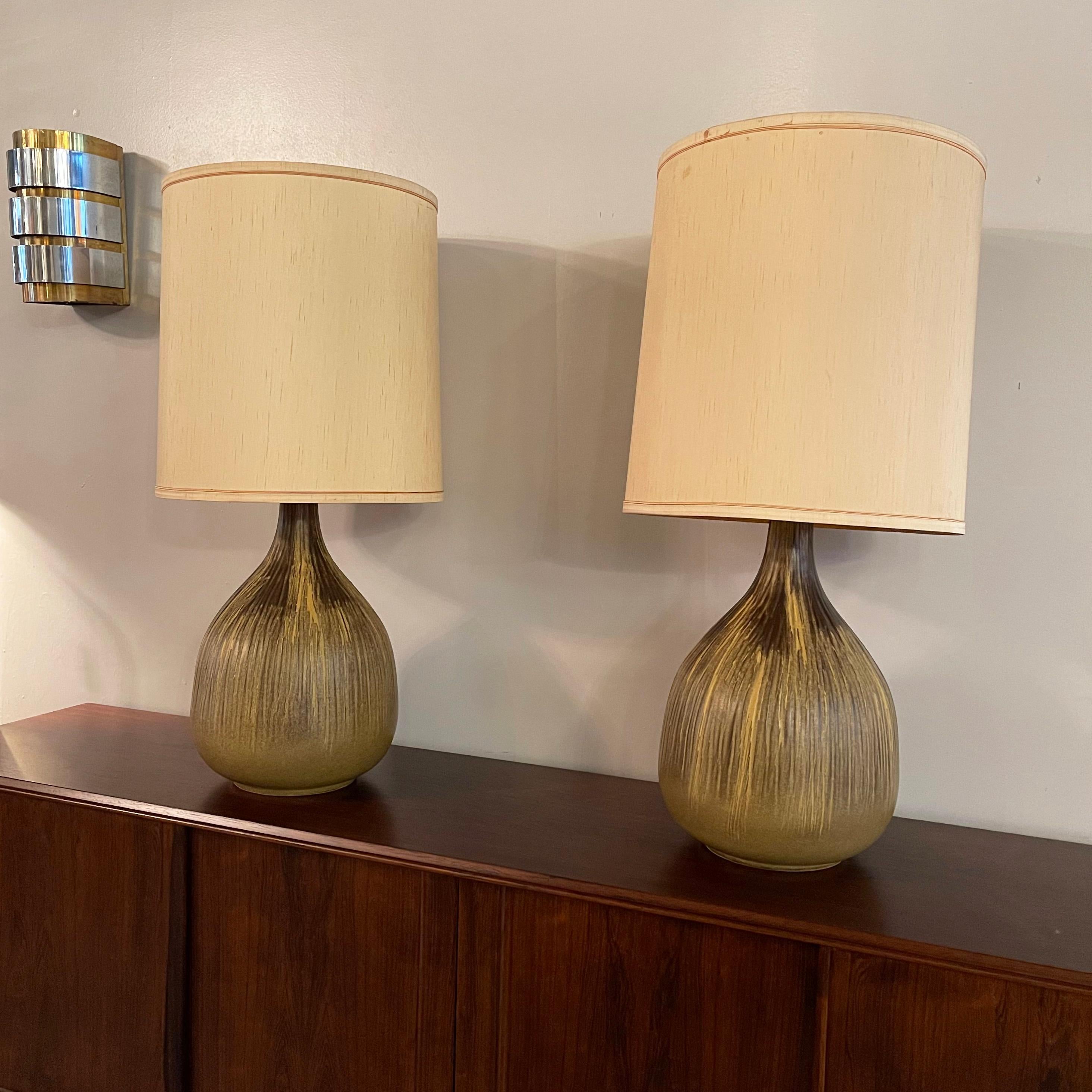 Pair of large, Mid-Century Modern table lamps feature art pottery, green gourd shaped and textured bases, wood necks, brass hardware and raw silk fabric shades. The height to the top of the socket is 22 inches.
