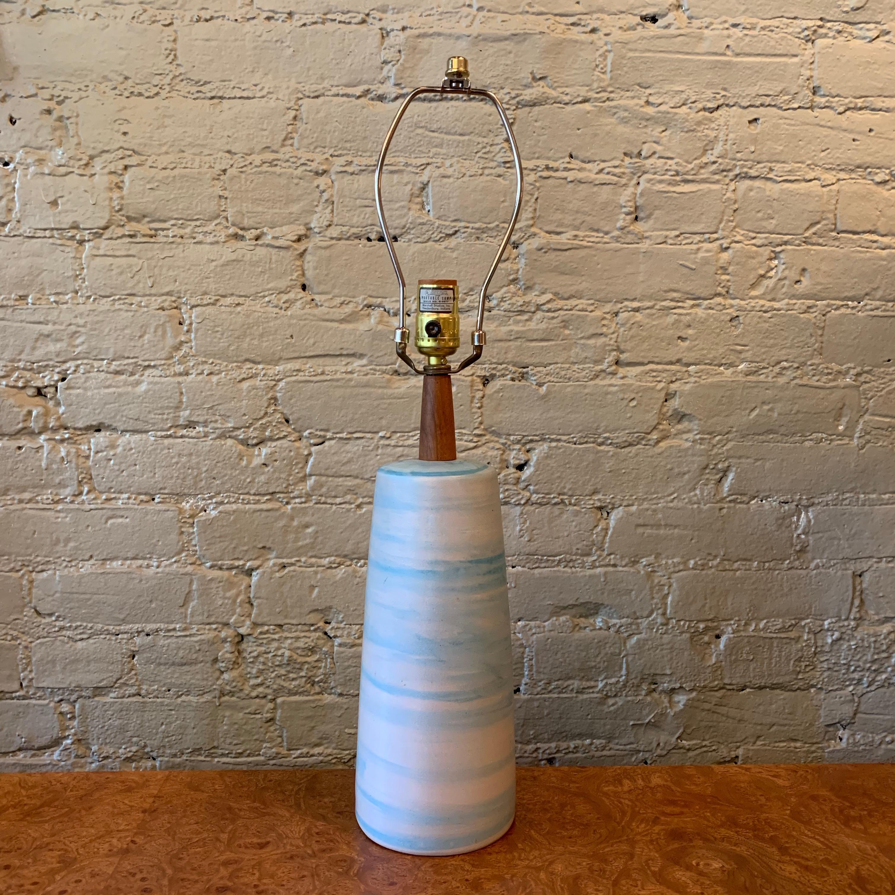 Mid-Century Modern, art pottery table lamp by Gordon Martz for Marshall Studios features a swirled light blue, ceramic base with teak neck and brass hardware. Height to the socket is 17 inches and overall height is 23 inches.