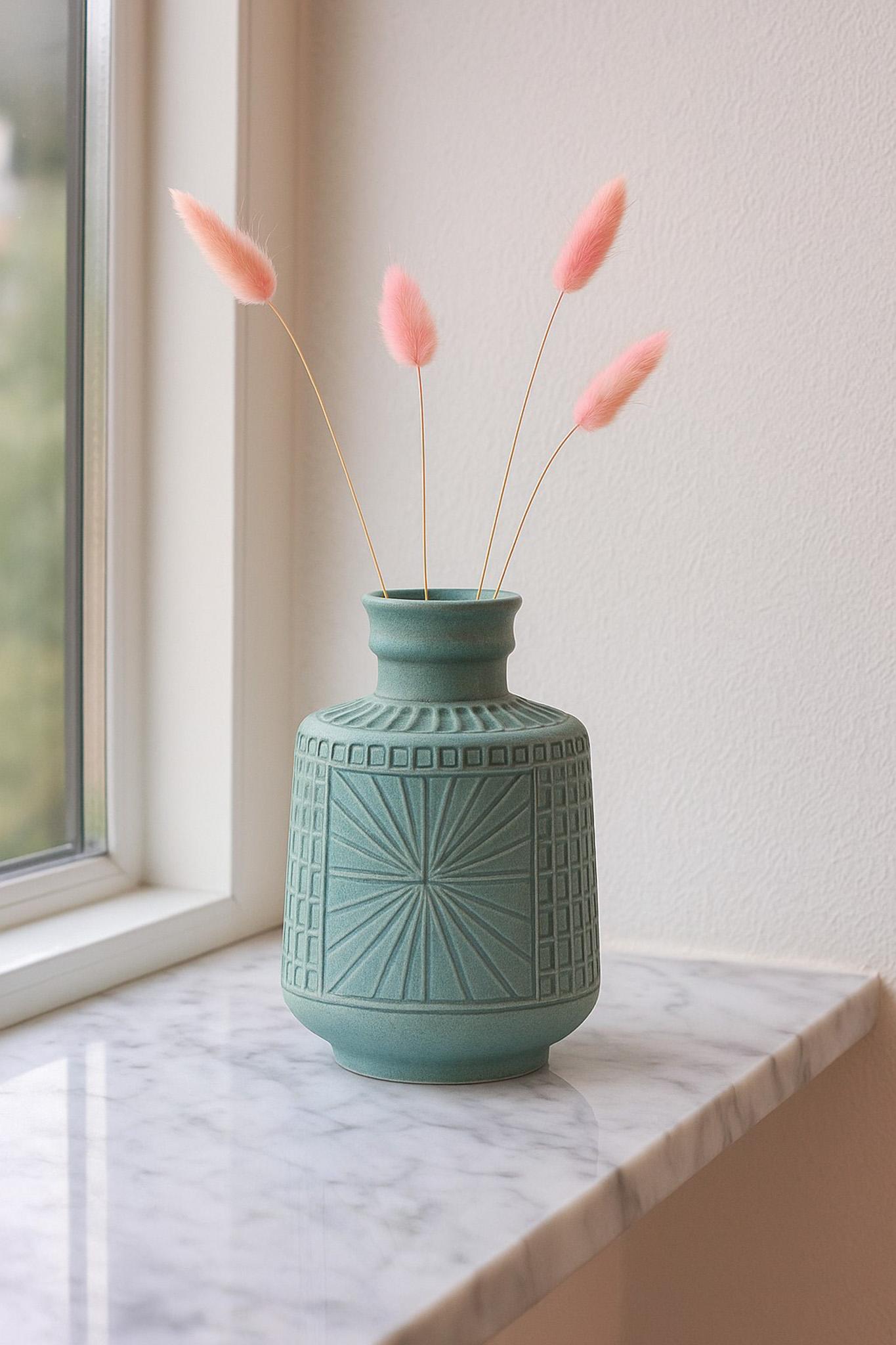 Un joli vase vintage fait main, réalisé par la talentueuse et célèbre artiste Mari Simmulson pour le tout aussi célèbre Upsala Ekeby dans les années 60. Il présente un glaçage fantastique avec des détails étonnants dans une couleur turquoise pâle.