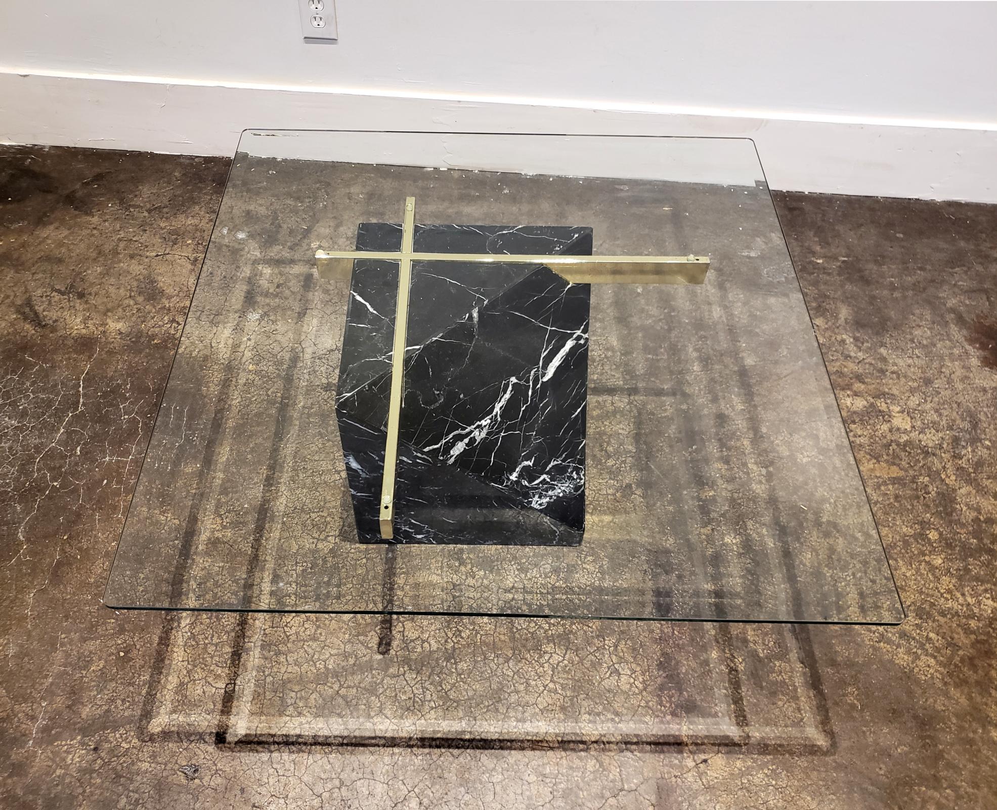 Artedi black marble coffee table, circa 1980s. Trapezoidal base of richly white-veined black marble with brass support elements. Square, beveled glass top.