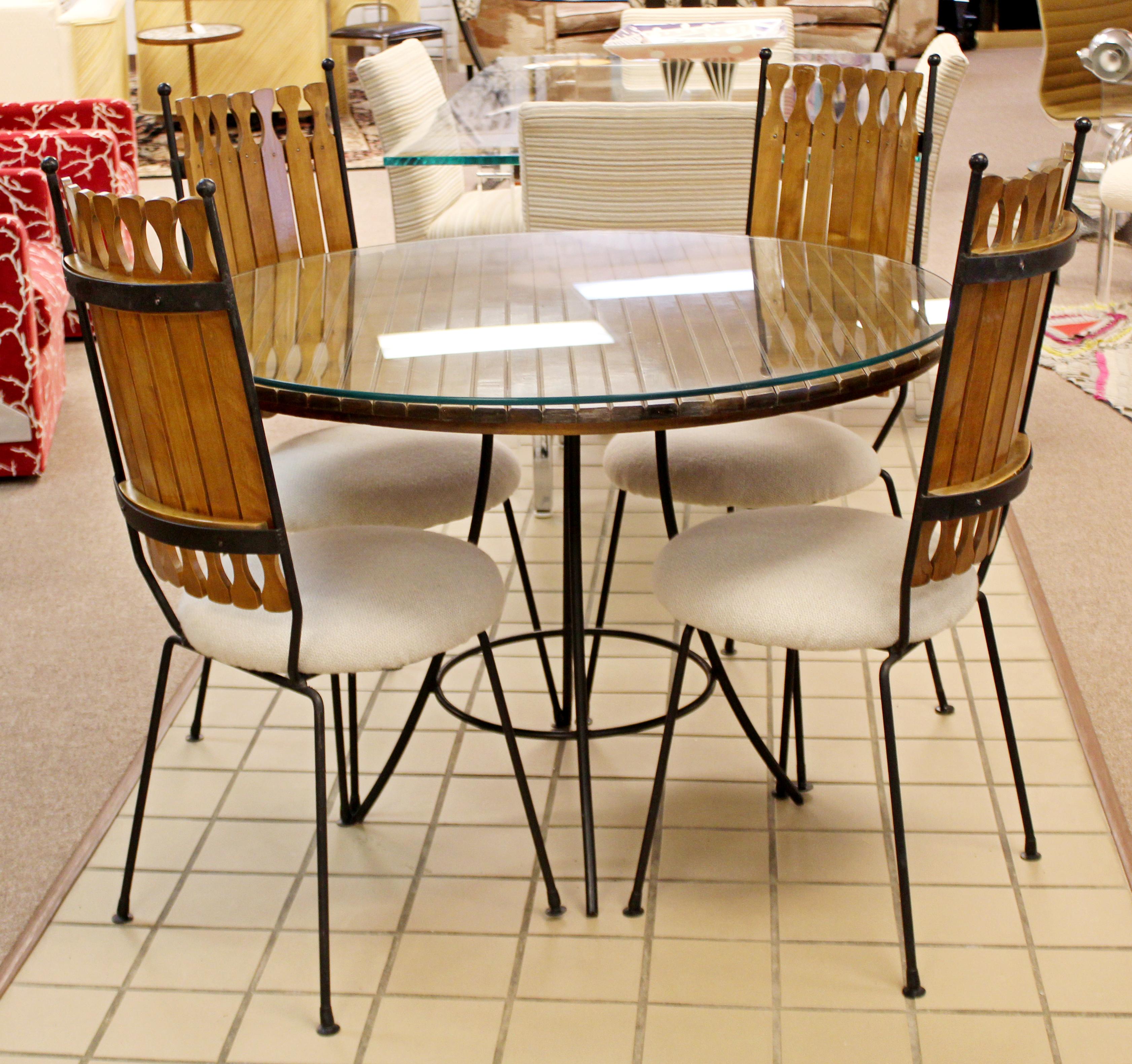 For your consideration is a spectacular dinette set, including four iron side chairs, and an iron and wood slat table with a glass top, by Arthur Umanoff, circa 1960s. In very good vintage condition. The dimensions of the table are 42